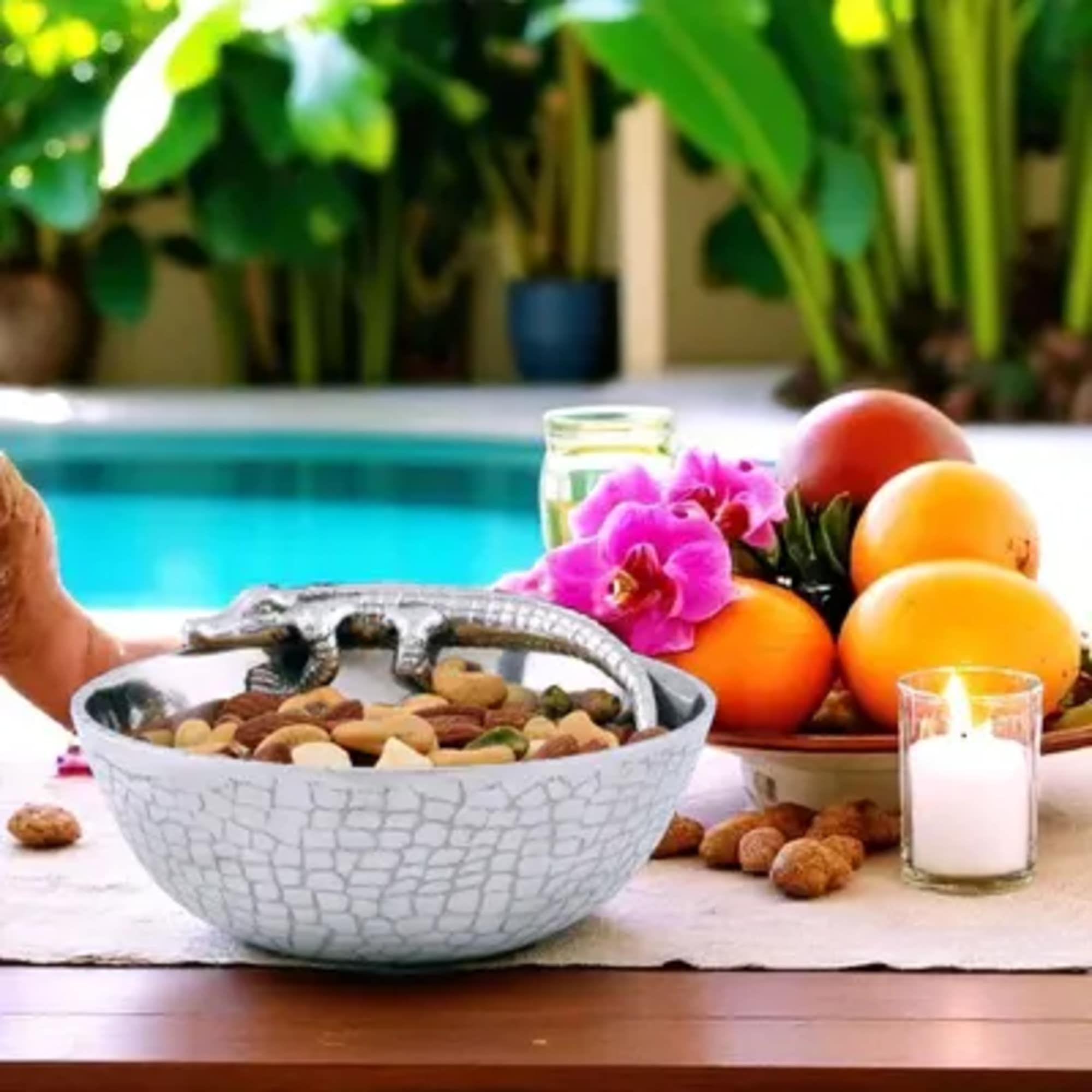 Fruit bowl with orchids, a candle, and a decorative lizard figurine