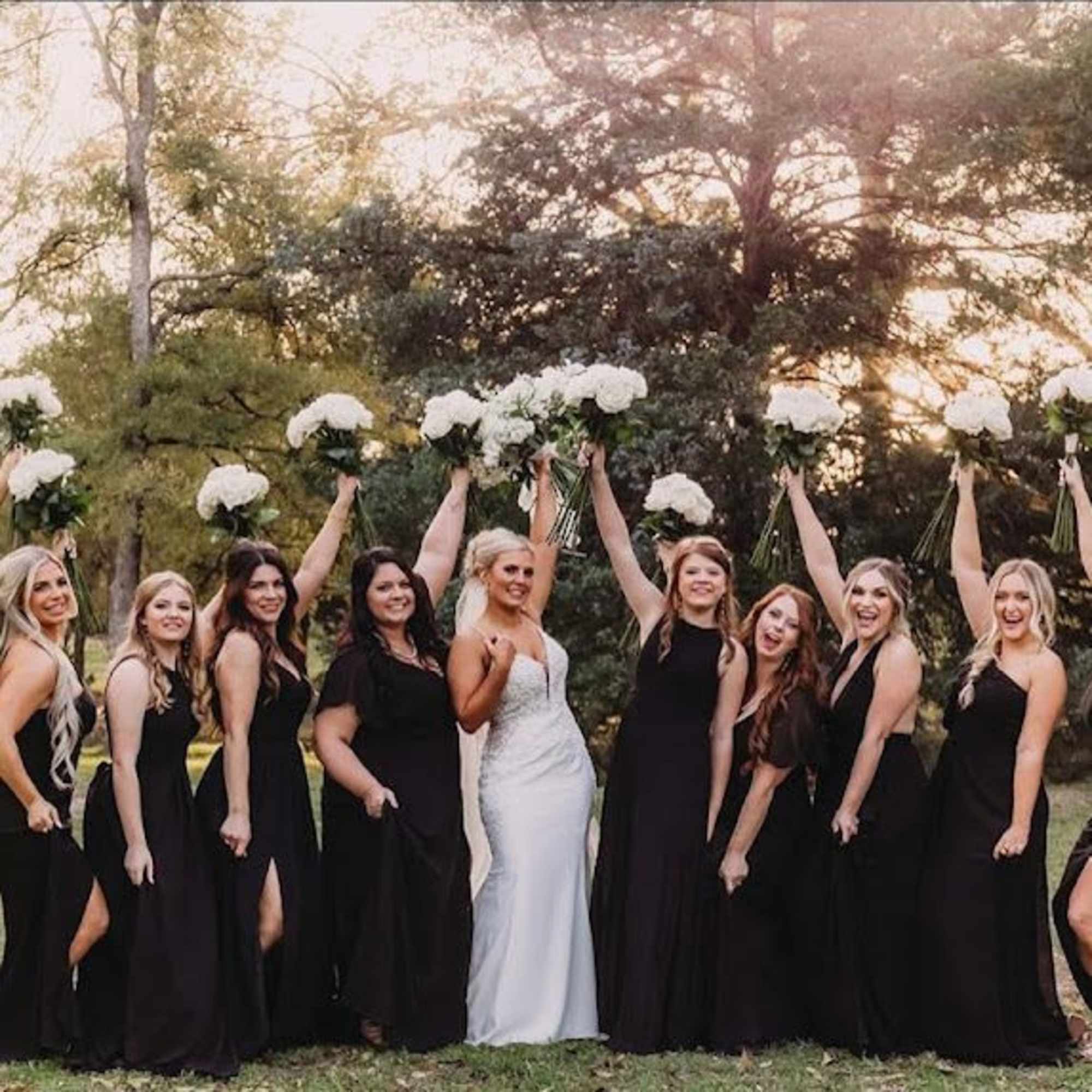 Bride and bridesmaids holding white bouquets outdoors