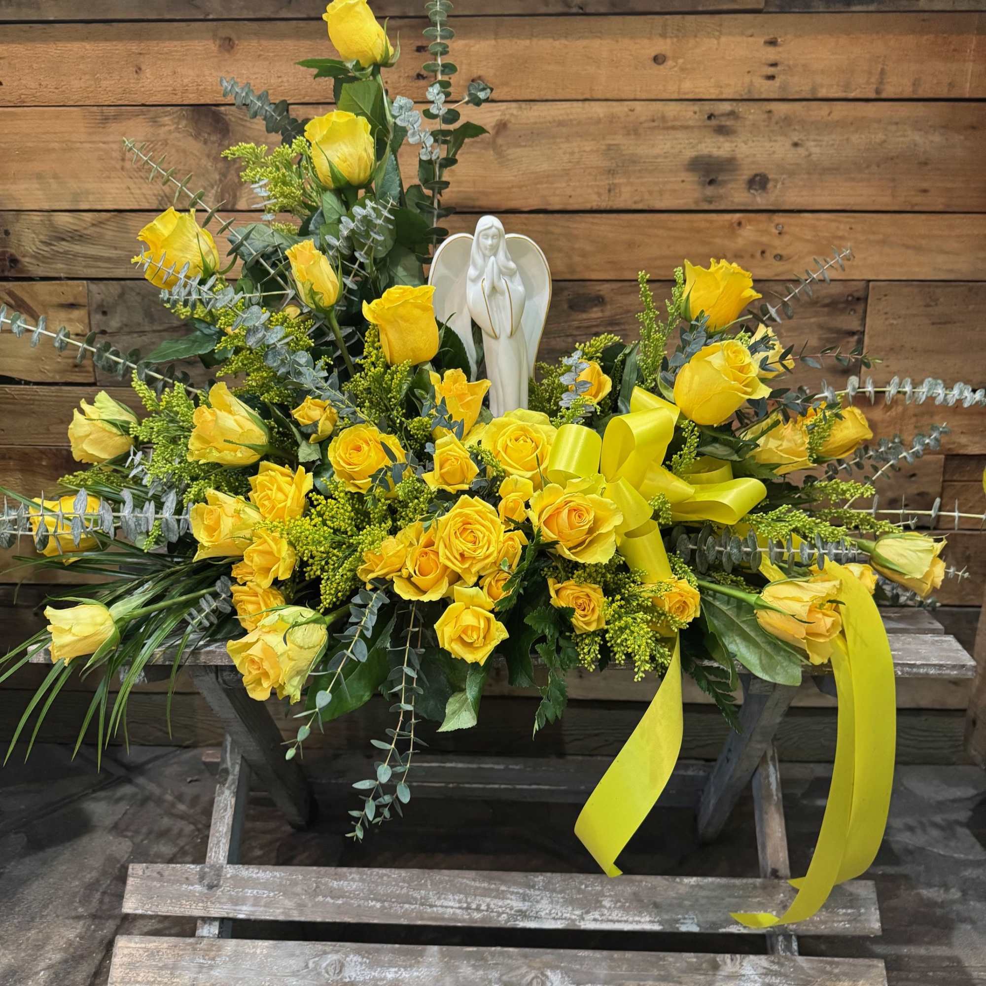 Yellow rose arrangement with a white angel figurine and ribbon