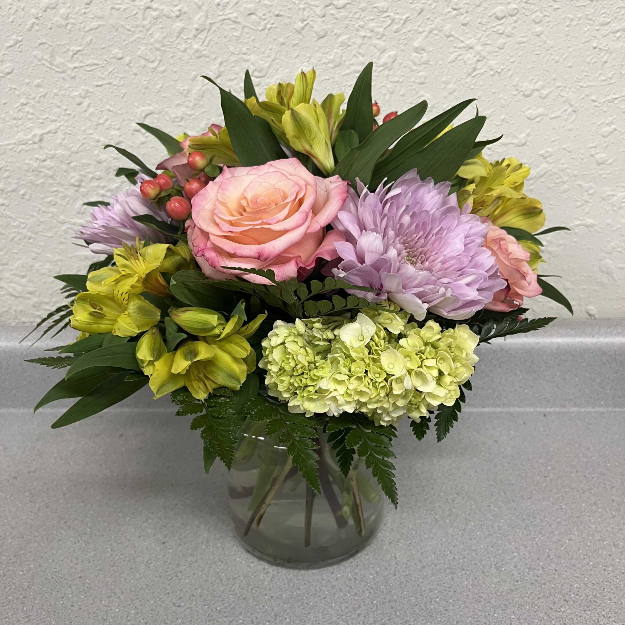 A rounded cluster of pink roses and a pale green hydrangea creates