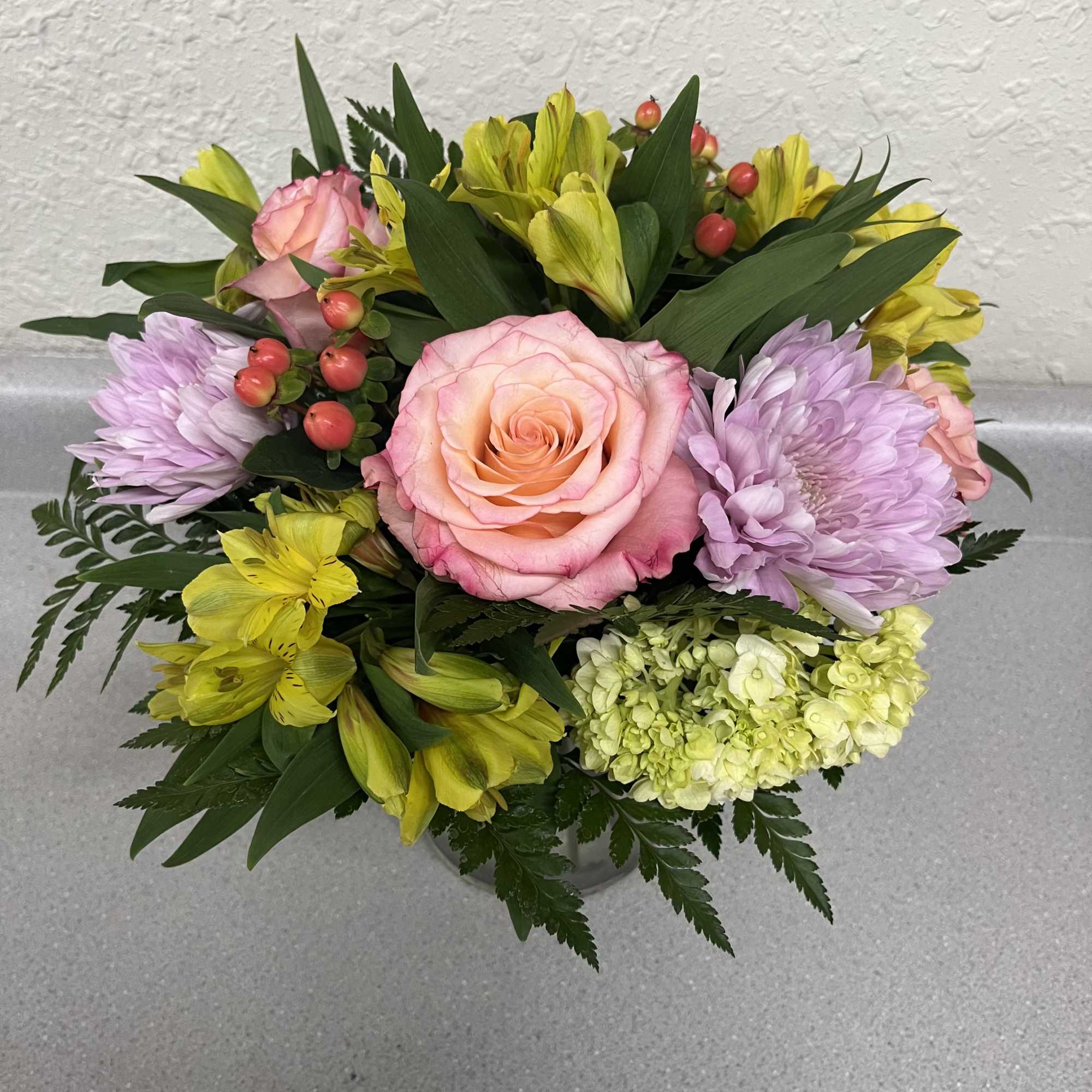 A rounded cluster of pink roses and a pale green hydrangea creates