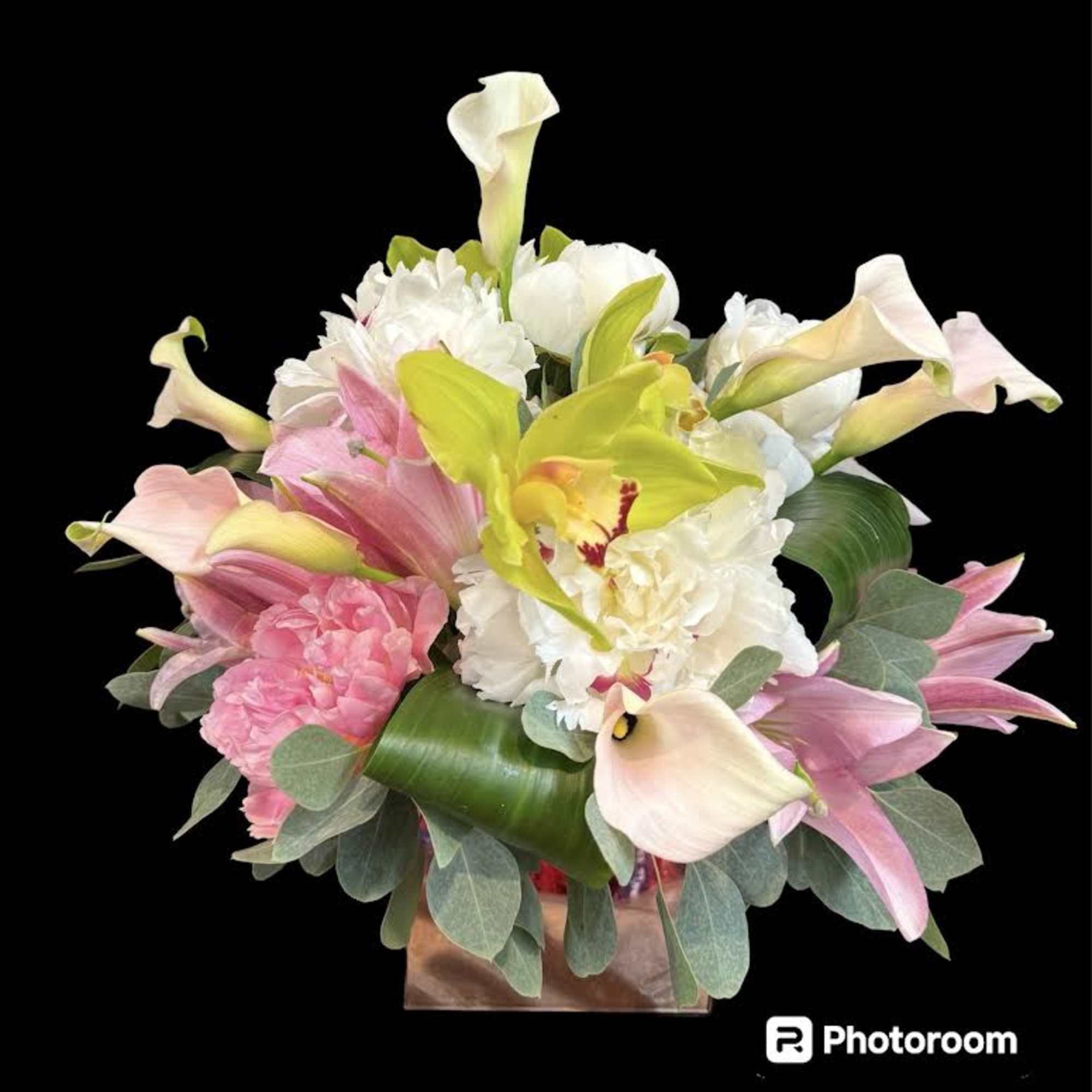 Pink and white calla lilies with white blooms in a square vase