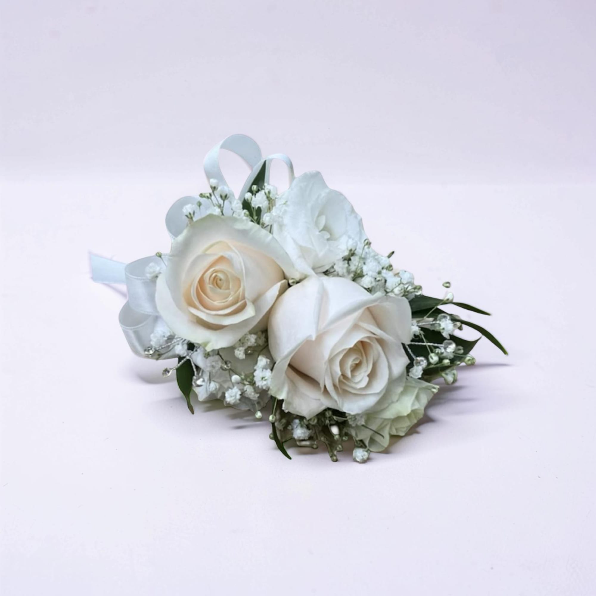 A soft and elegant corsage featuring ivory roses, delicate baby&rsquo;s breath, and