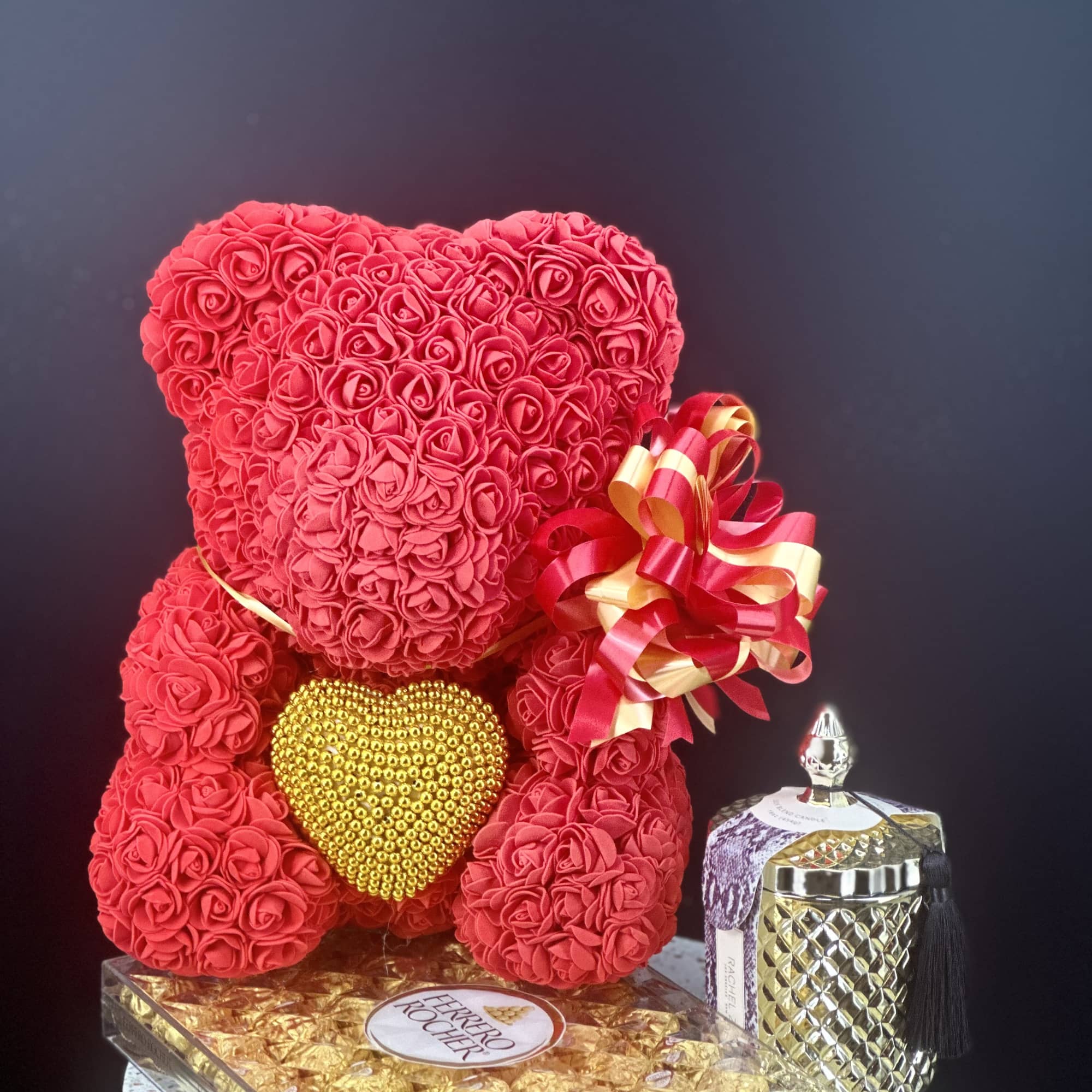 Red rose teddy bear with a gold heart and ribbon bow beside a perfume bottle