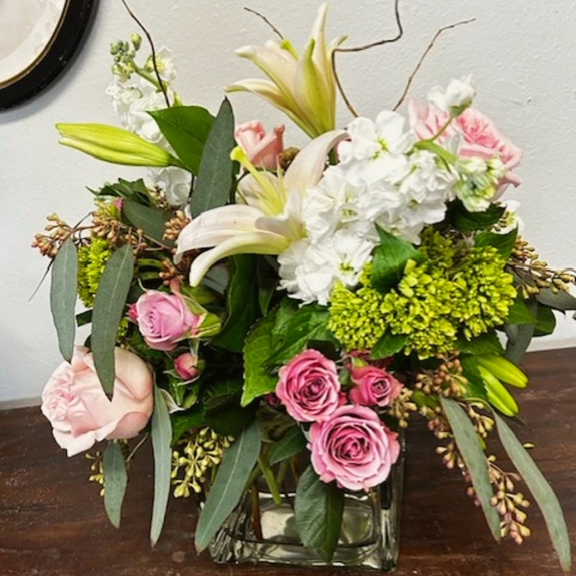 Mixed bouquet with pink roses, white lilies, and white hydrangea in a glass vase