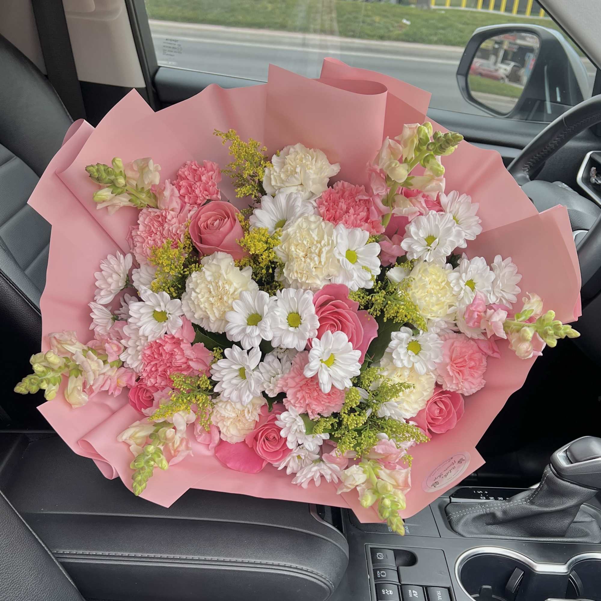 Pink bouquet with white daisies and carnations wrapped in pink paper
