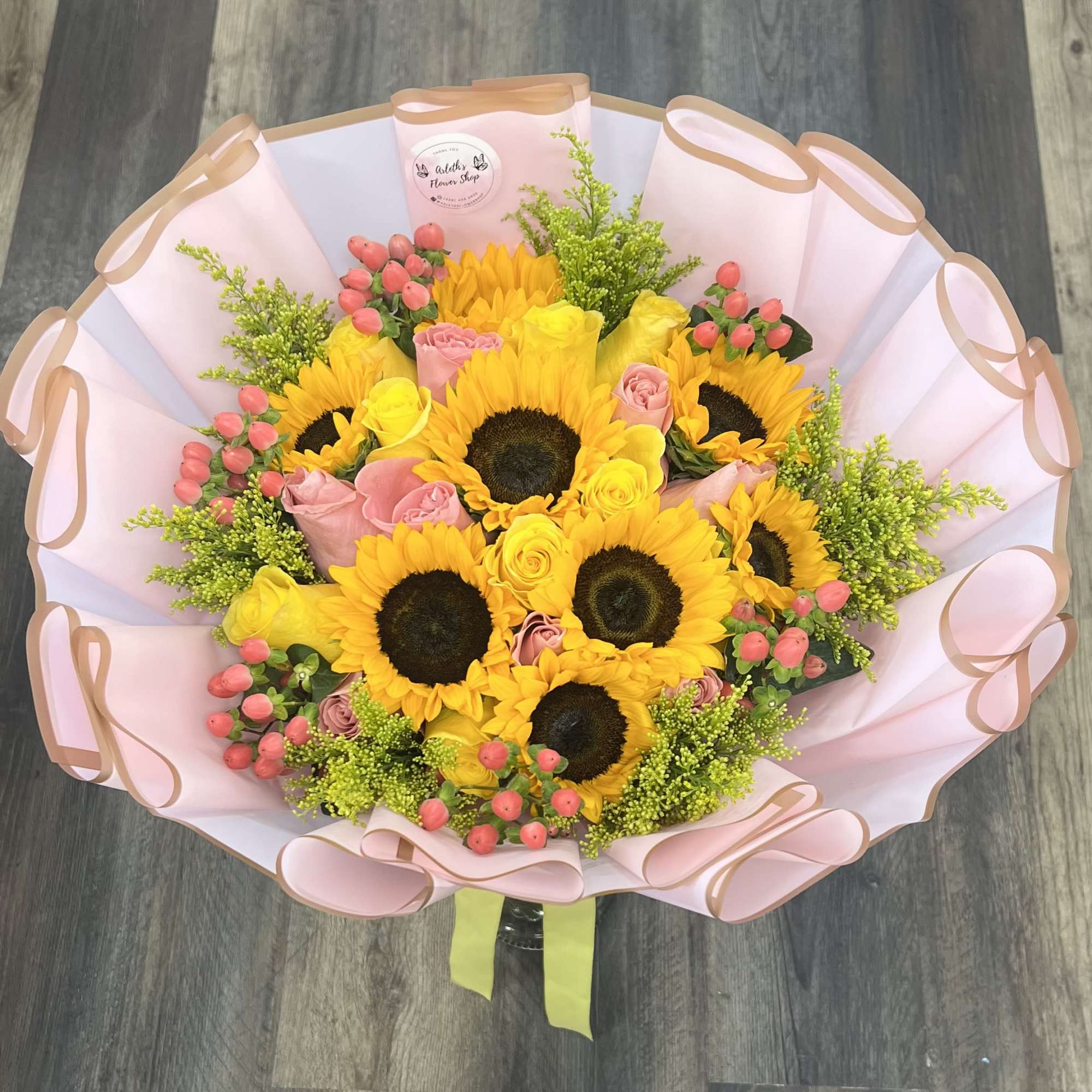 Bouquet of sunflowers and pink roses wrapped in pale pink paper