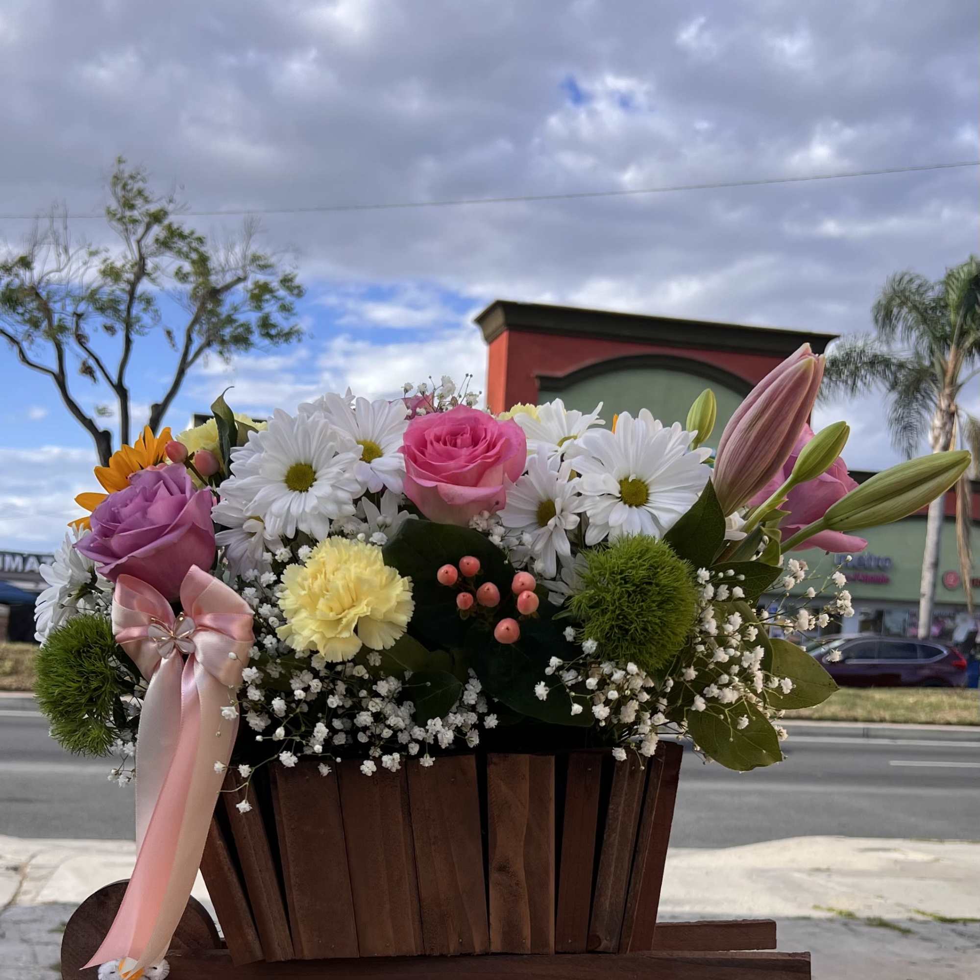 A bright and cheerful mix of sunflowers, roses, and delicate blooms, made