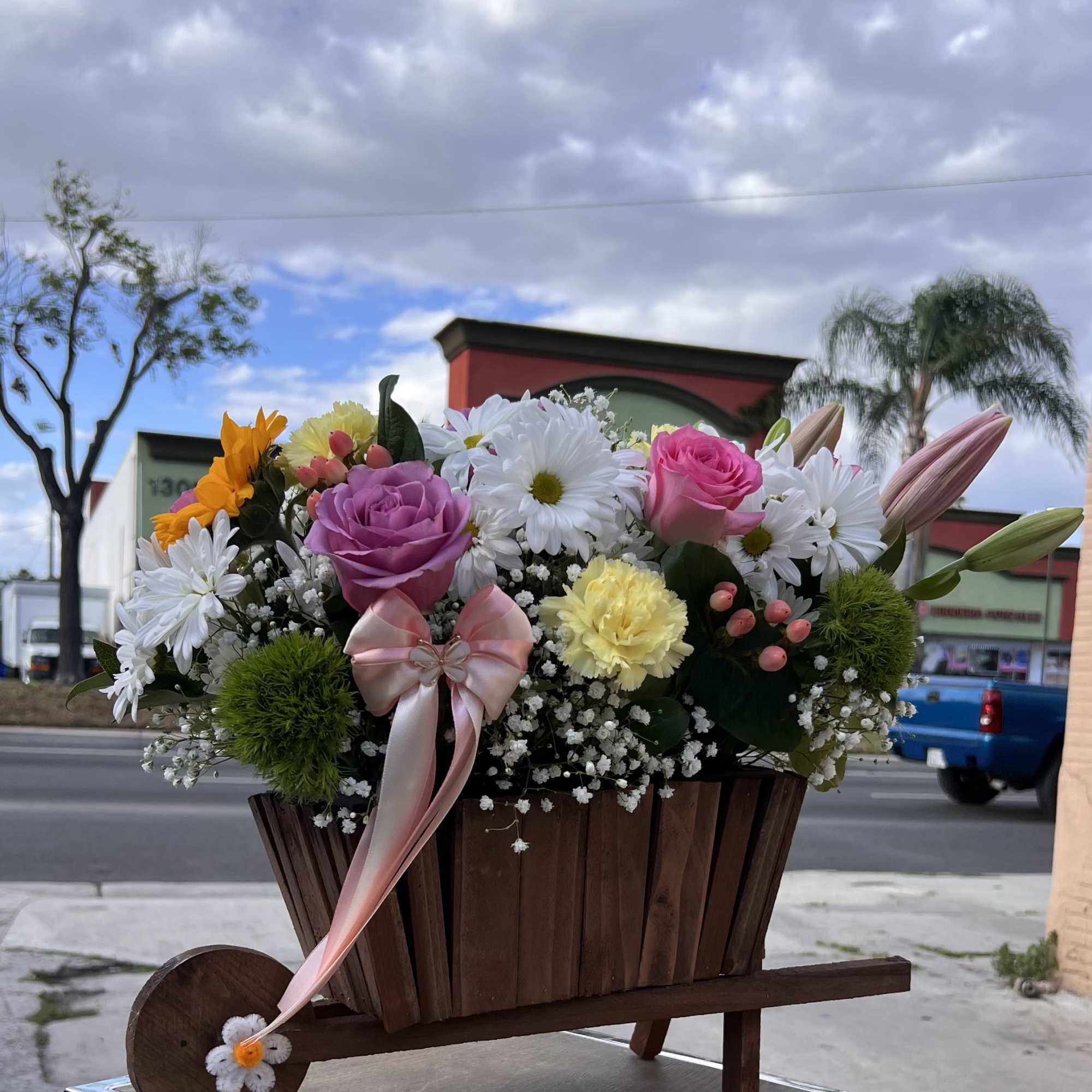 A bright and cheerful mix of sunflowers, roses, and delicate blooms, made