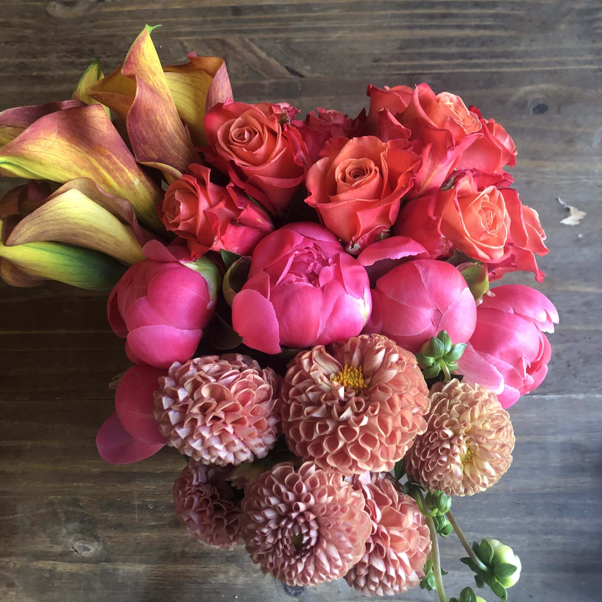 Bouquet of pink roses, peonies, and peach dahlias with calla lilies