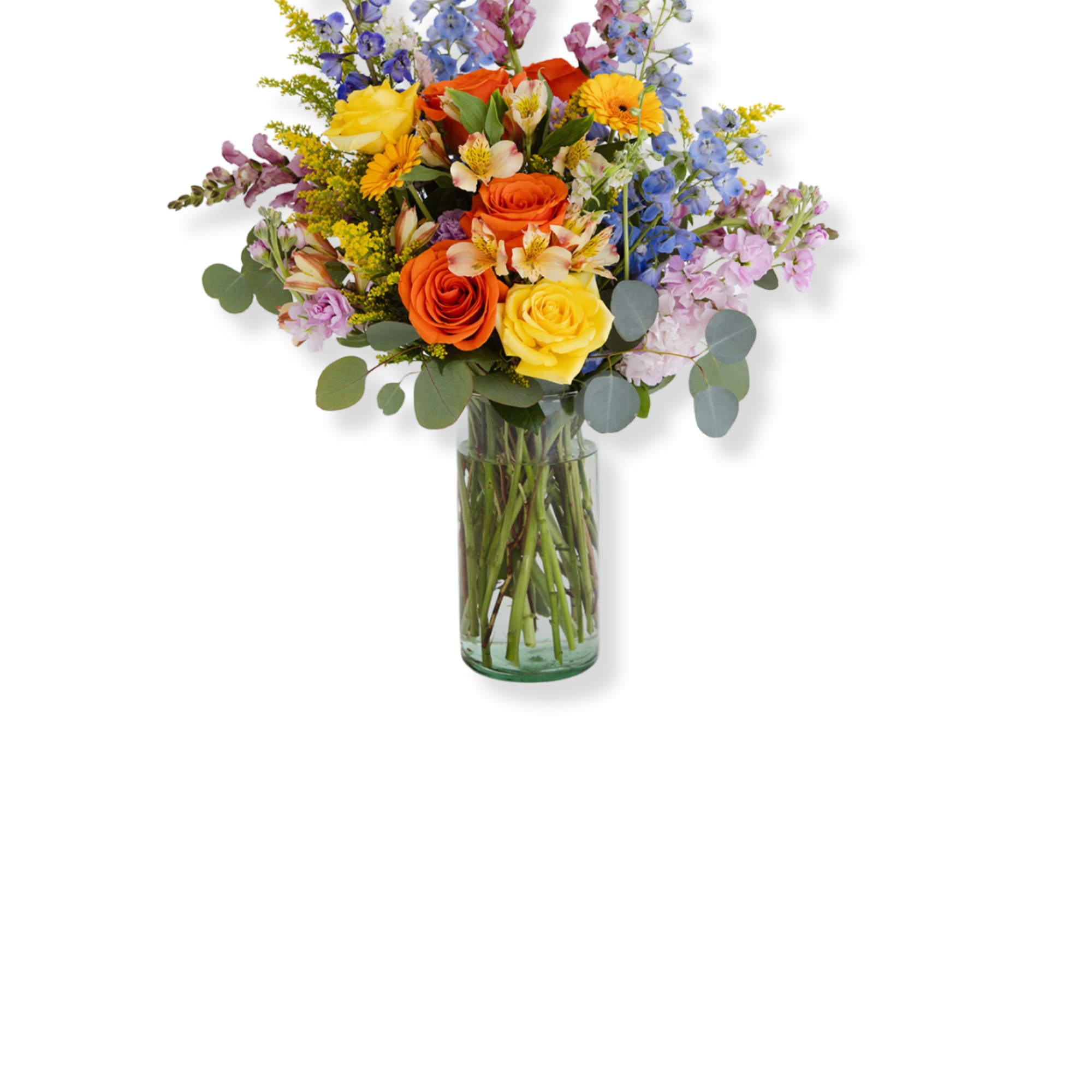 Tall mixed bouquet of yellow and orange roses with pastel blooms in a clear glass vase