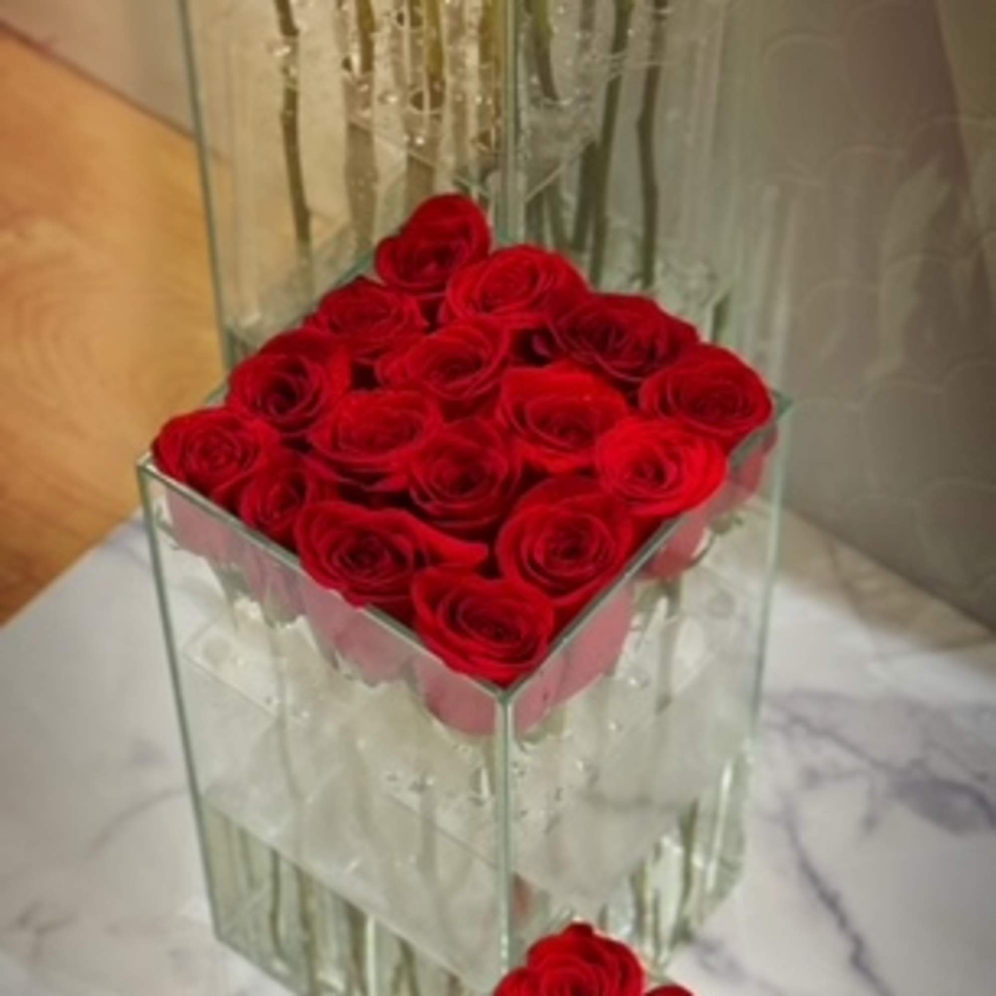 Three square glass vases filled with tightly packed red roses