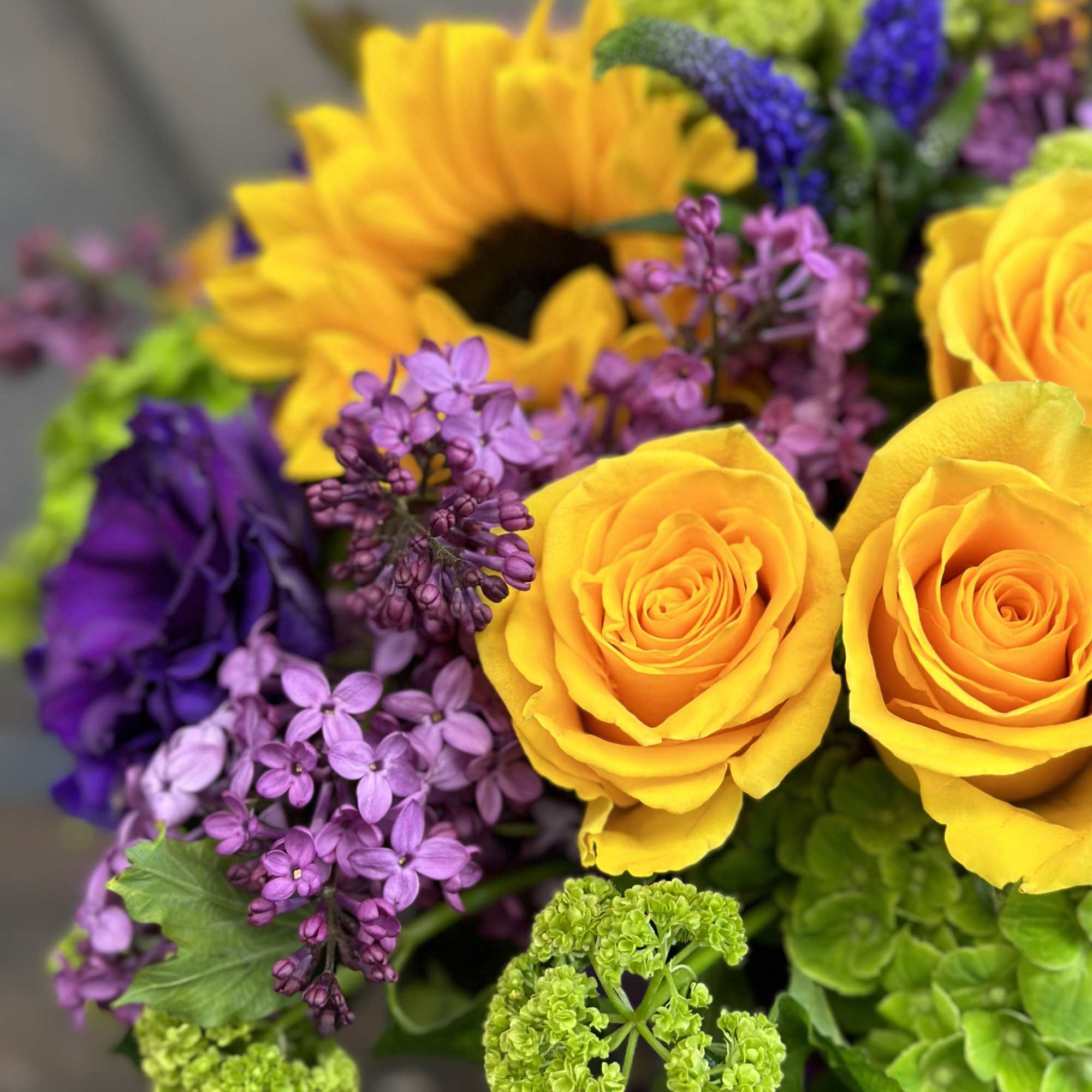 Bouquet of yellow roses, a sunflower, and purple flowers