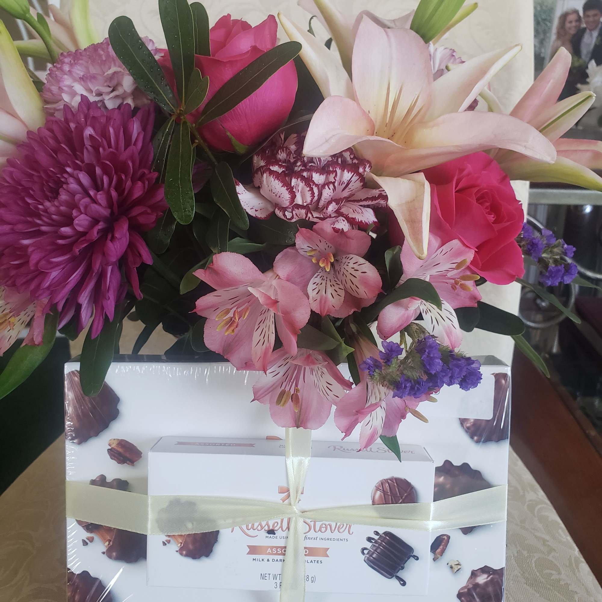 A lush cluster of pale pink lilies, bright pink roses and purple