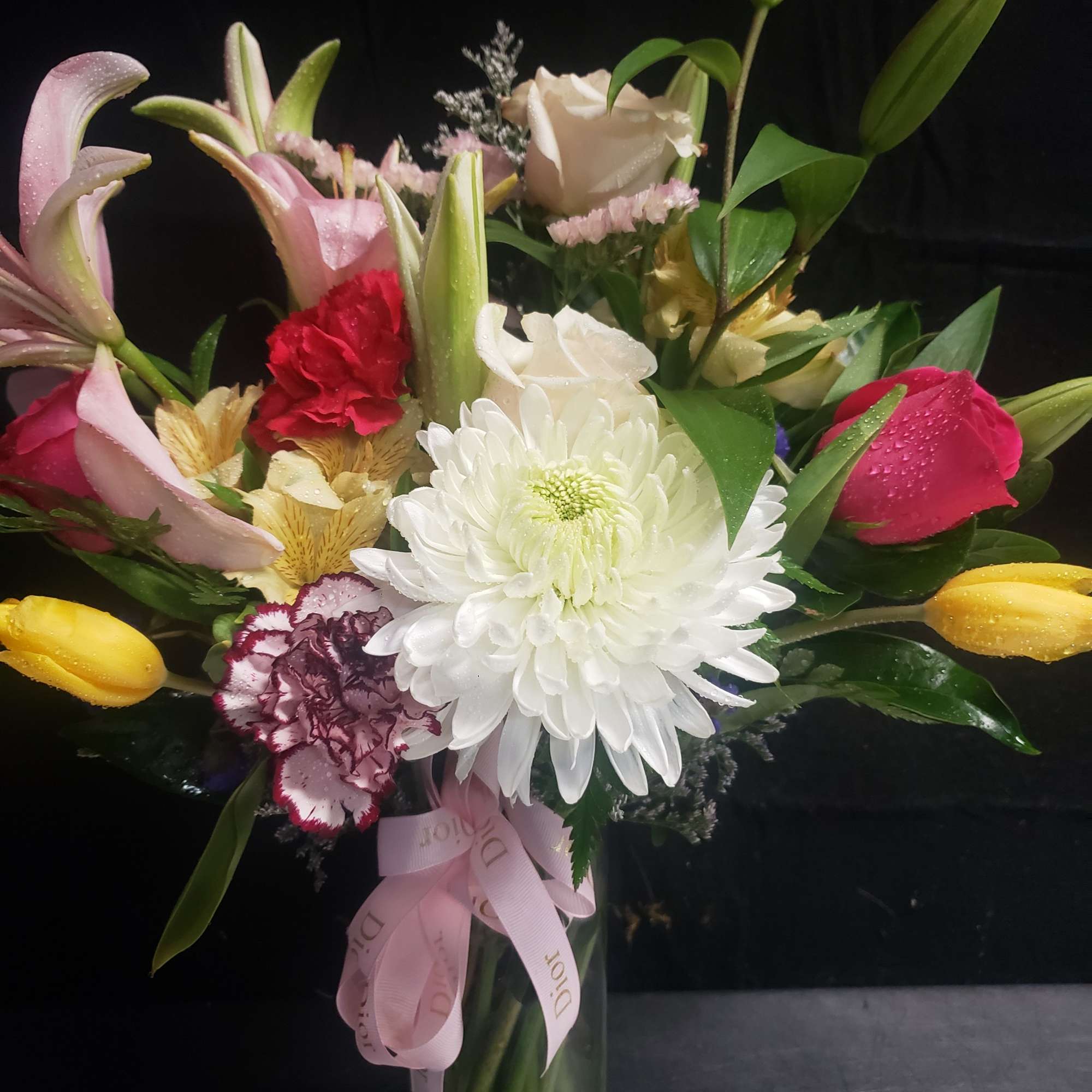 A lush cluster of white lilies and a large white chrysanthemum anchors