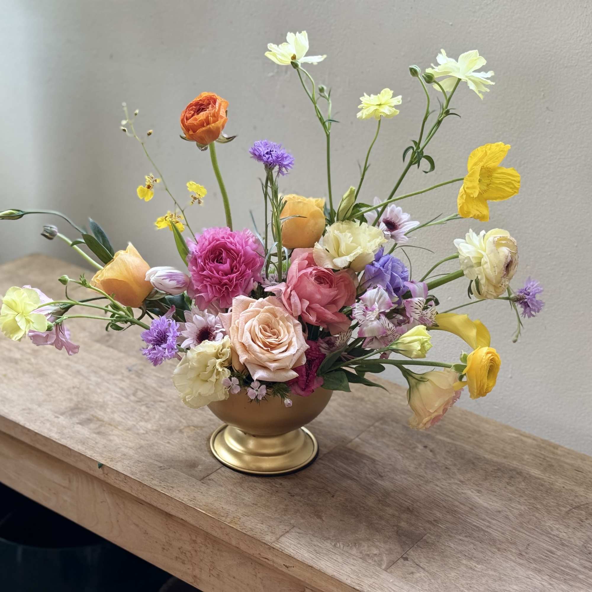 A loose, airy centerpiece of in-season blooms that greets the recipient with