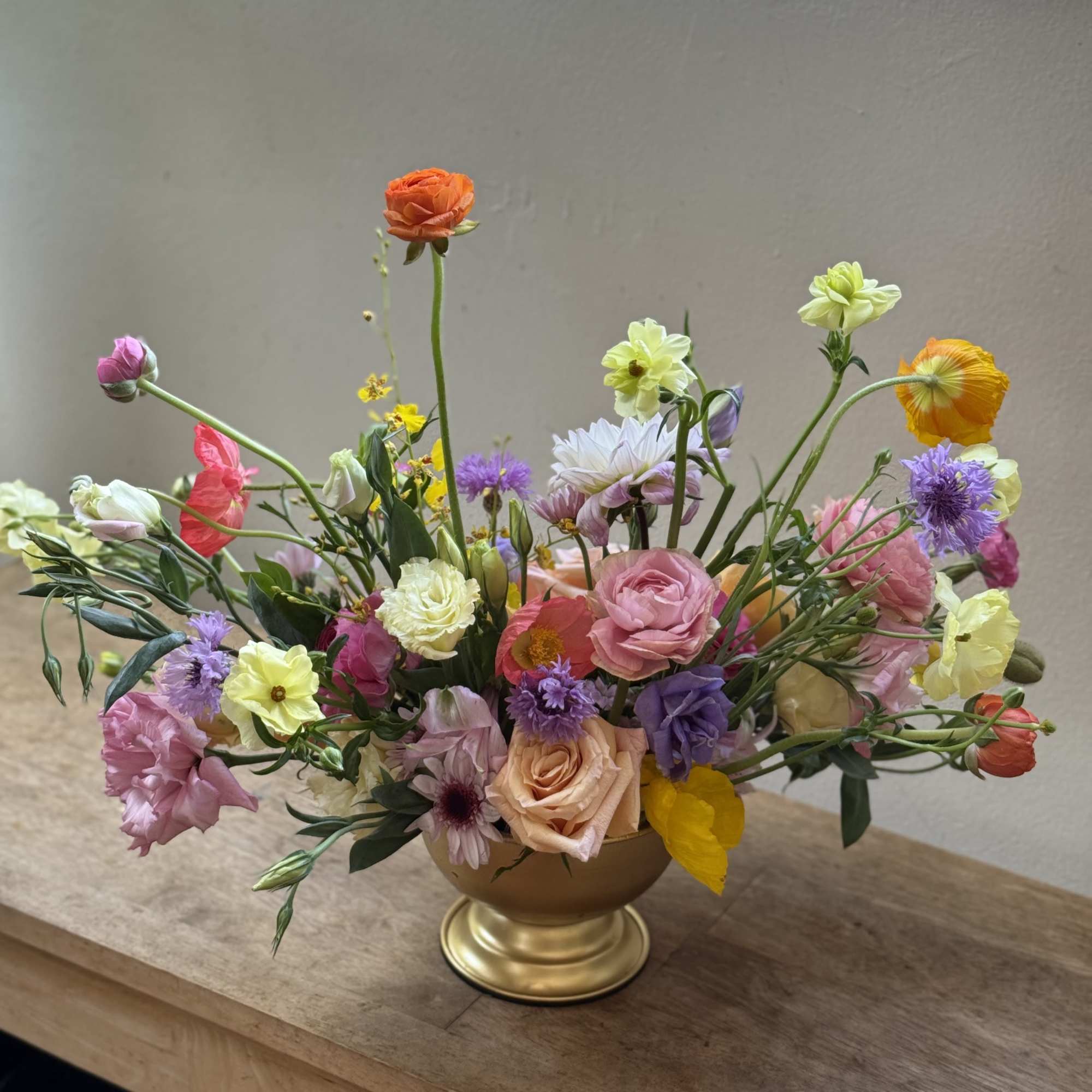A loose, airy centerpiece of in-season blooms that greets the recipient with
