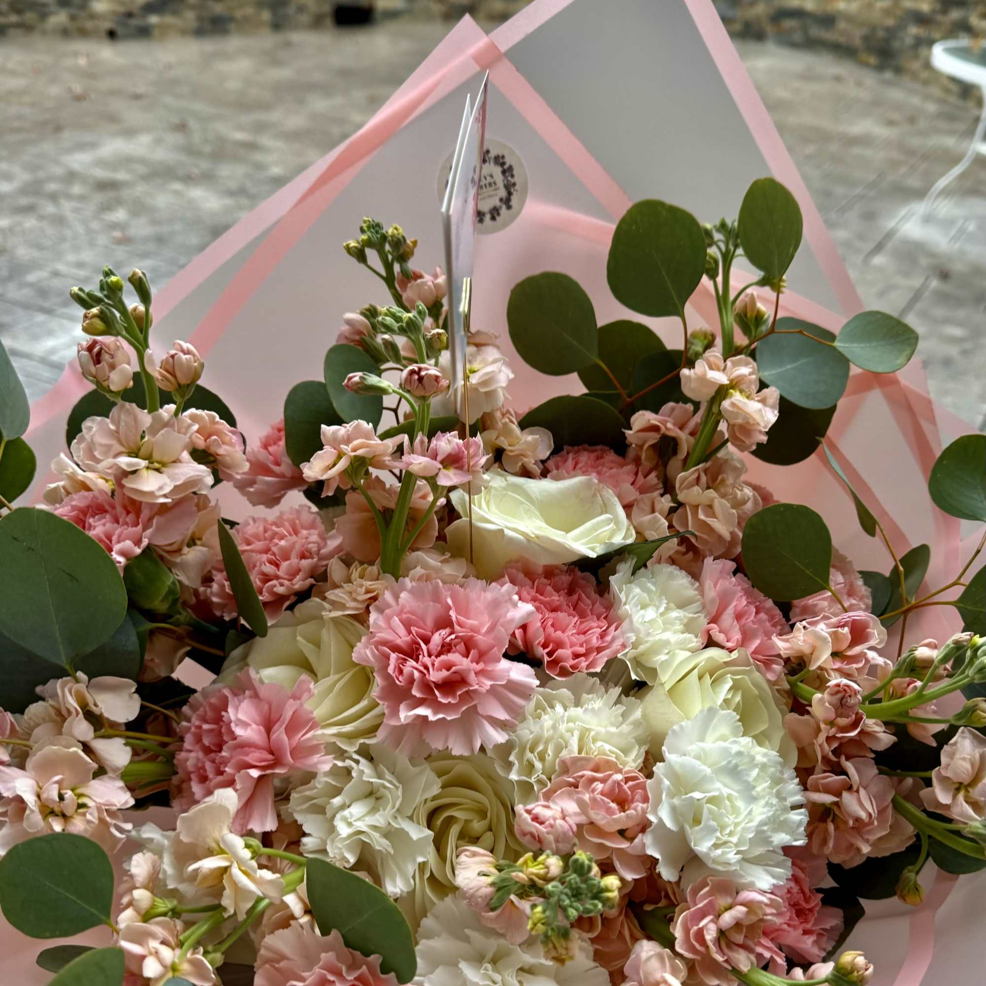 Pink and white bouquet with carnations, roses, and round eucalyptus leaves