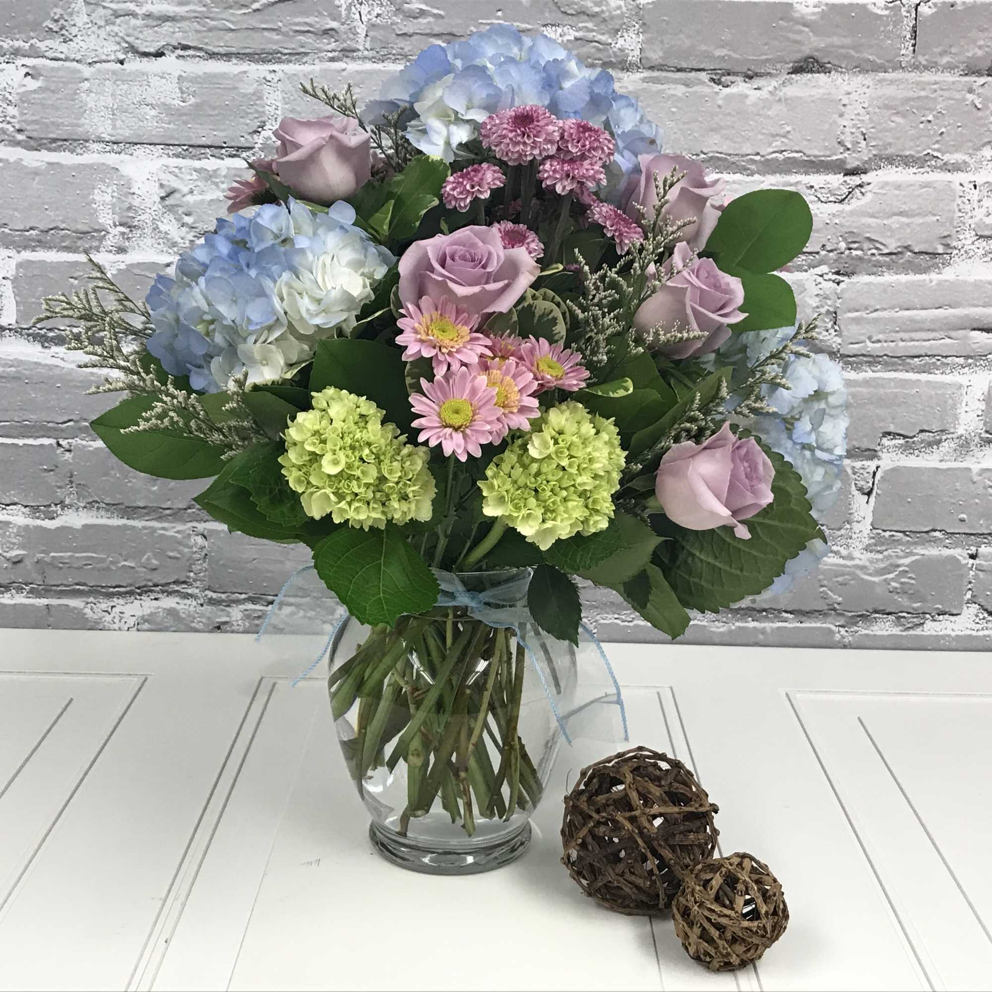 Mixed bouquet of pastel flowers in a clear glass vase