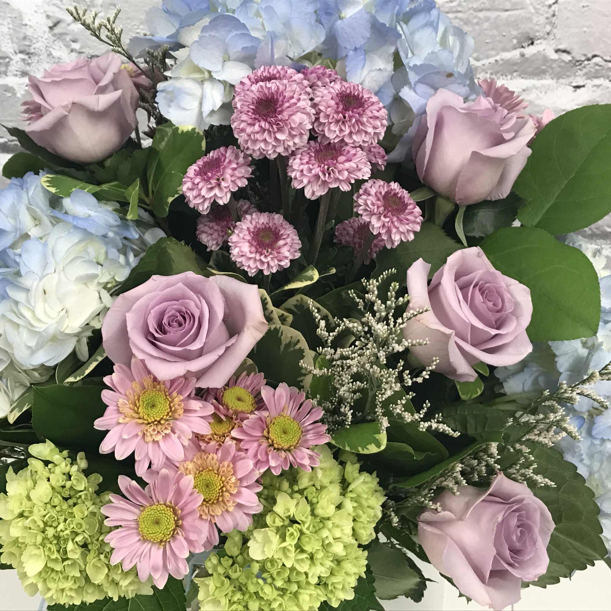 Bouquet of lavender roses, pink daisies, and blue hydrangeas