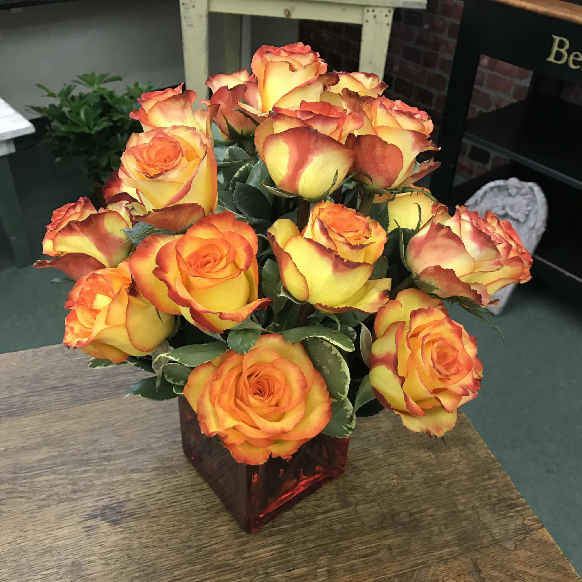 Bouquet of orange and yellow roses in a red glass vase