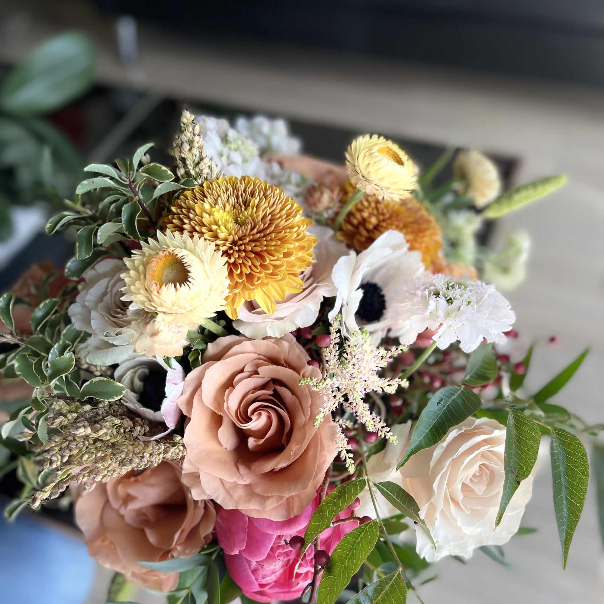 A luxurious garden-style bridal bouquet featuring warm blush roses, golden seasonal blooms