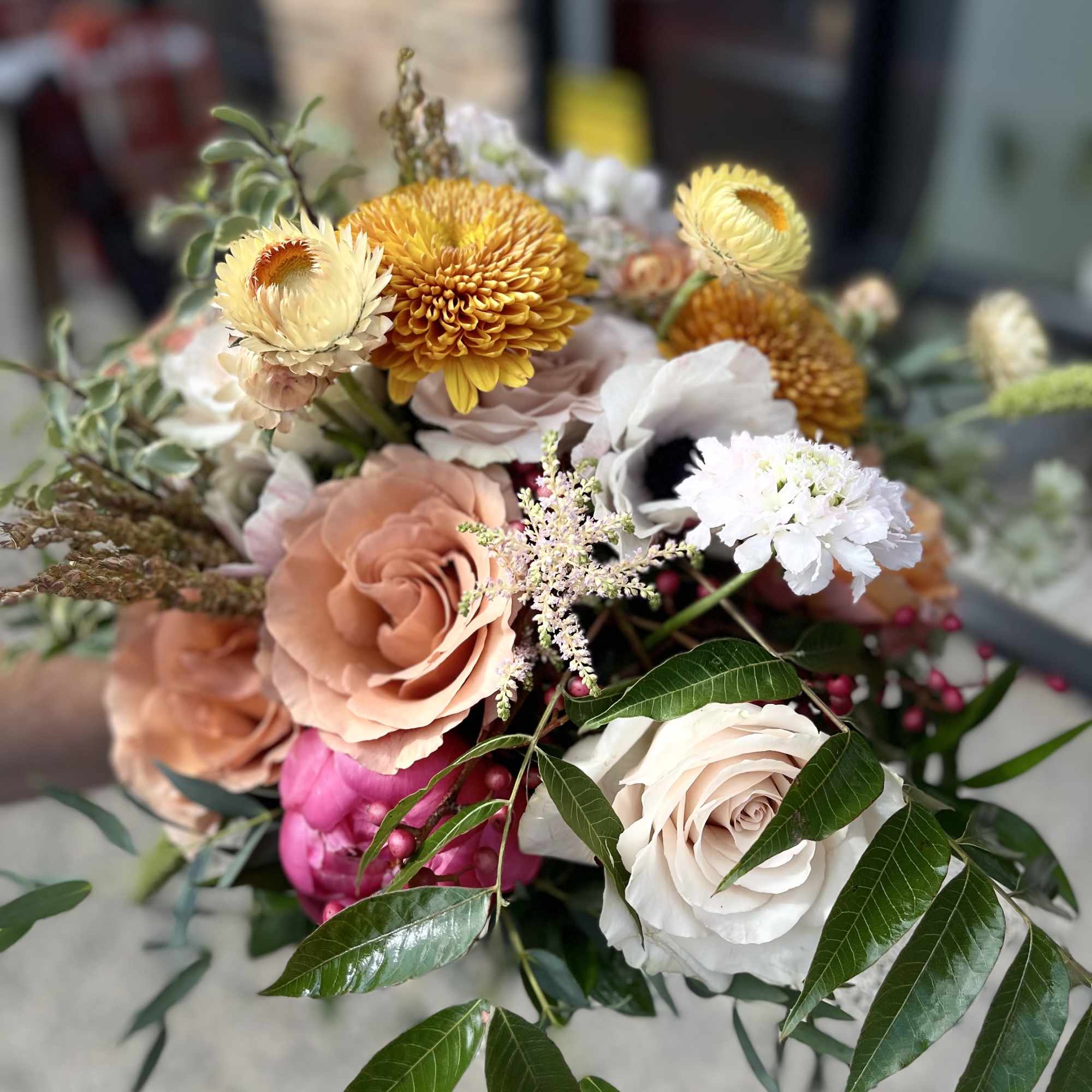 A luxurious garden-style bridal bouquet featuring warm blush roses, golden seasonal blooms