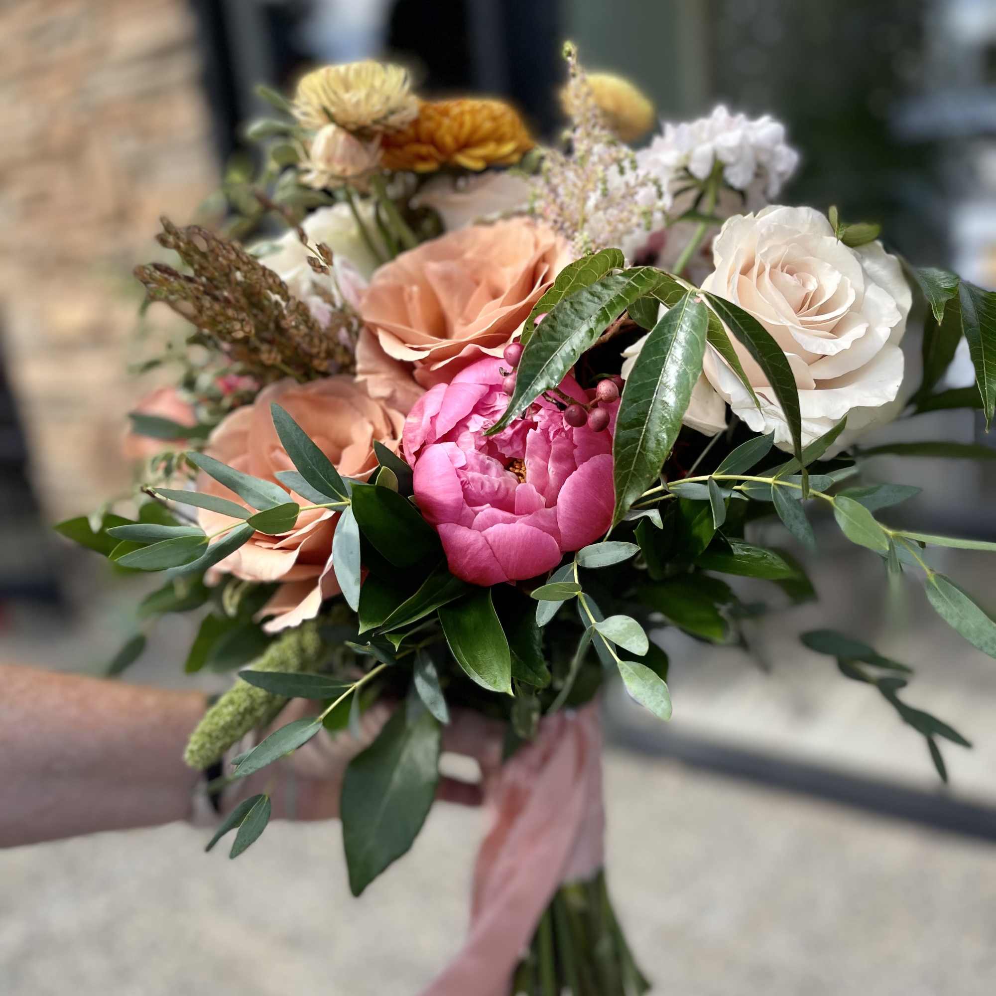 A luxurious garden-style bridal bouquet featuring warm blush roses, golden seasonal blooms