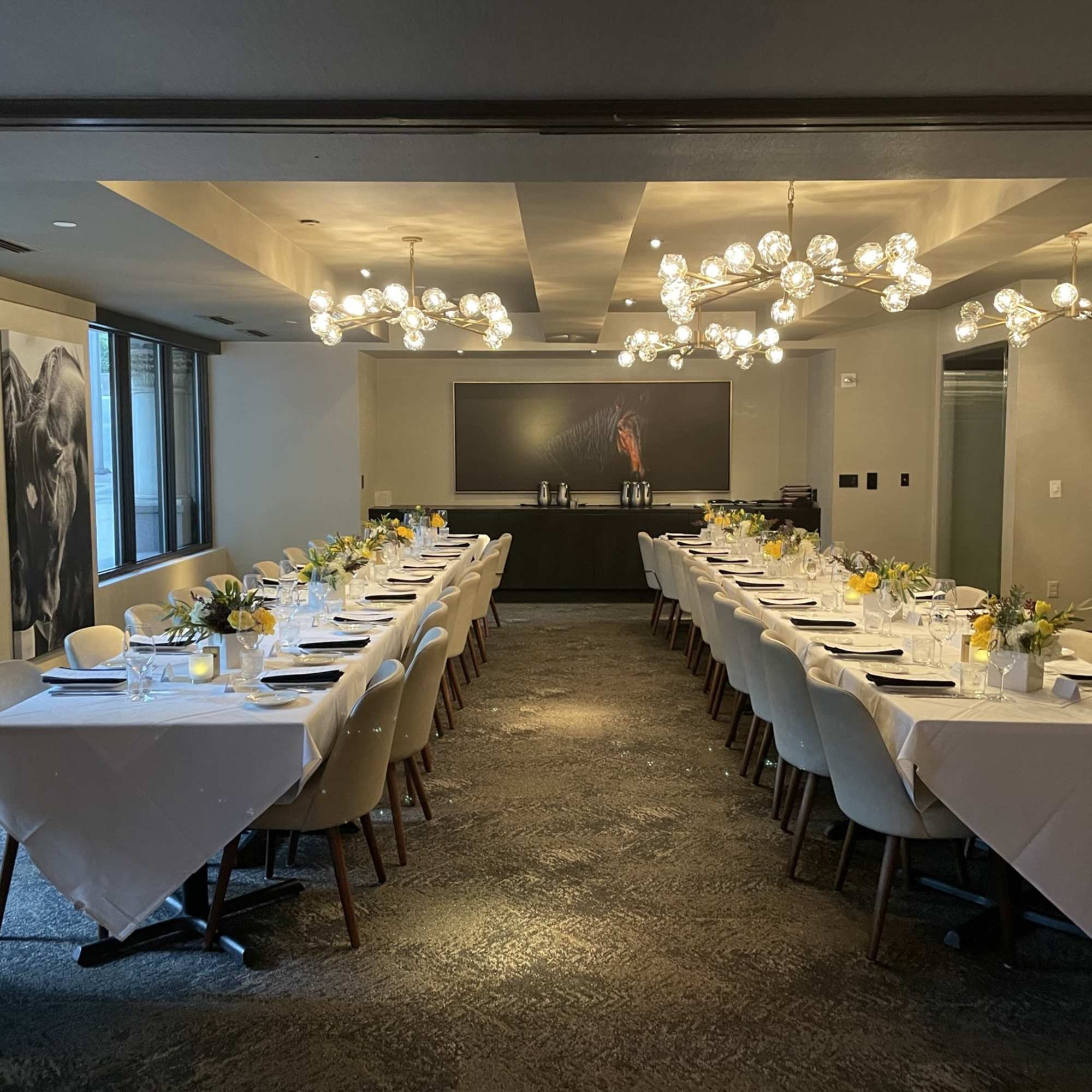 Long banquet tables set with small floral centerpieces in a modern dining room