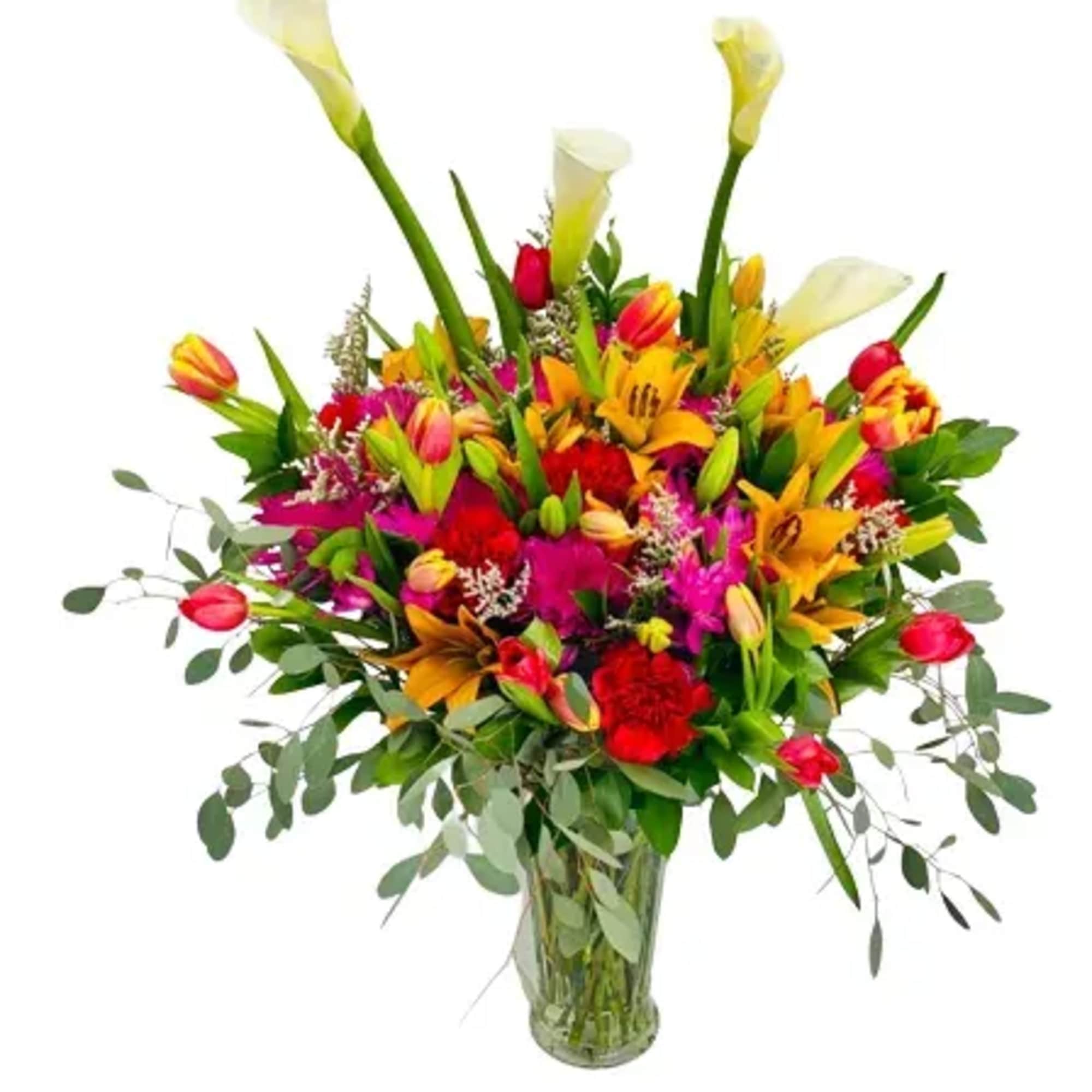 Colorful bouquet of lilies, tulips, and calla lilies in a glass vase