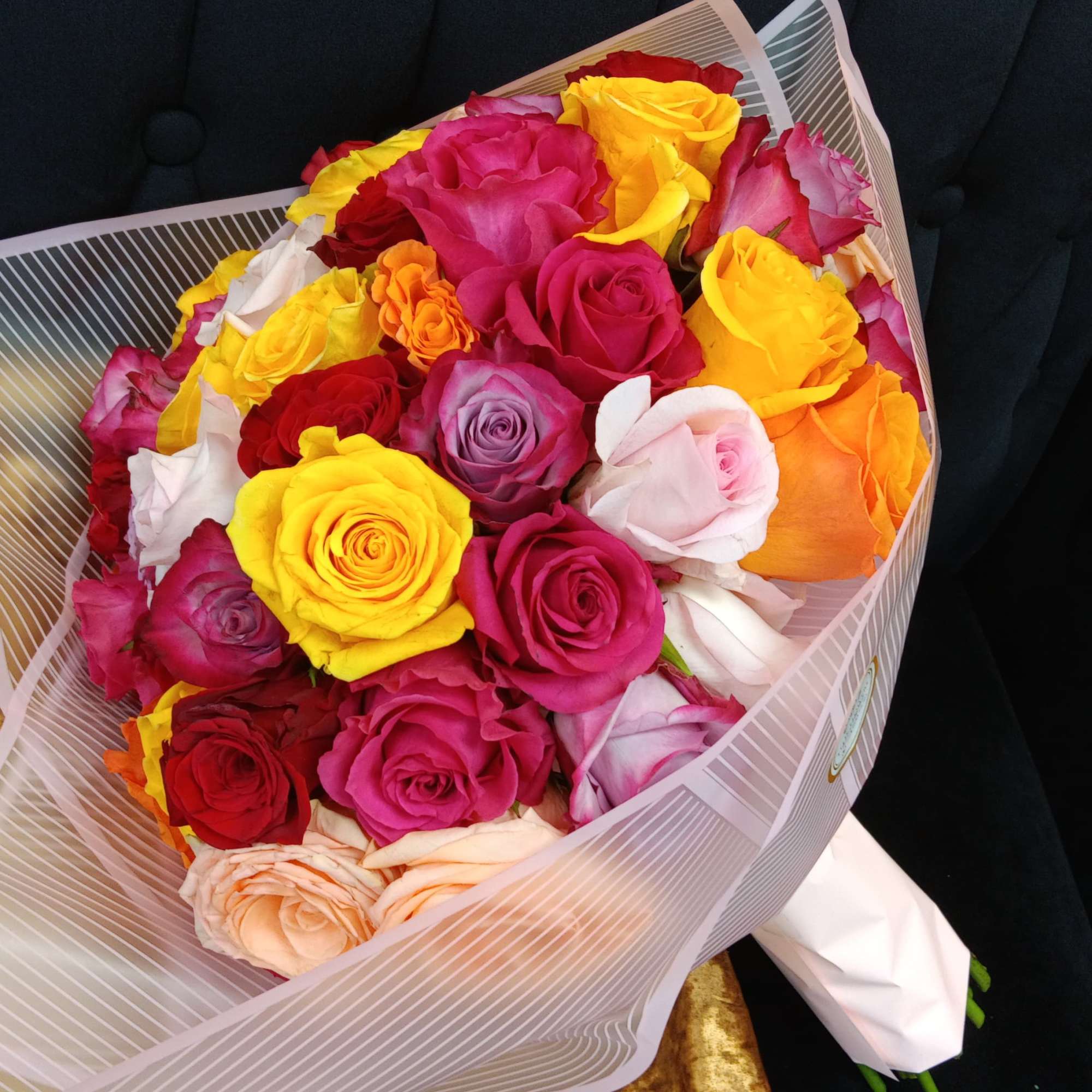 Bouquet of multicolored roses wrapped in striped paper