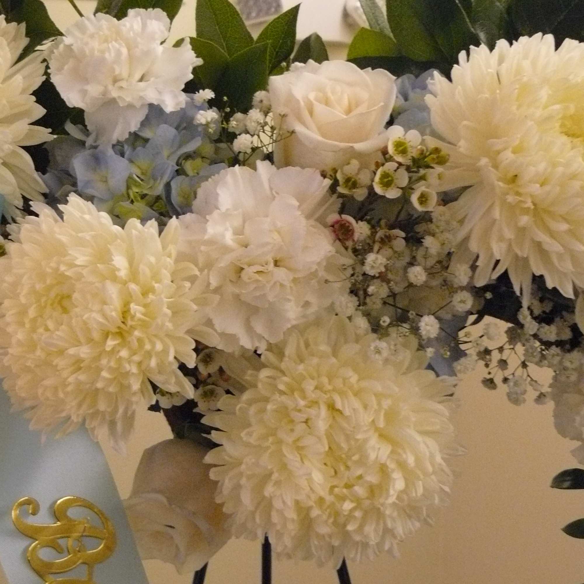 White floral arrangement with roses, chrysanthemums, and blue ribbon
