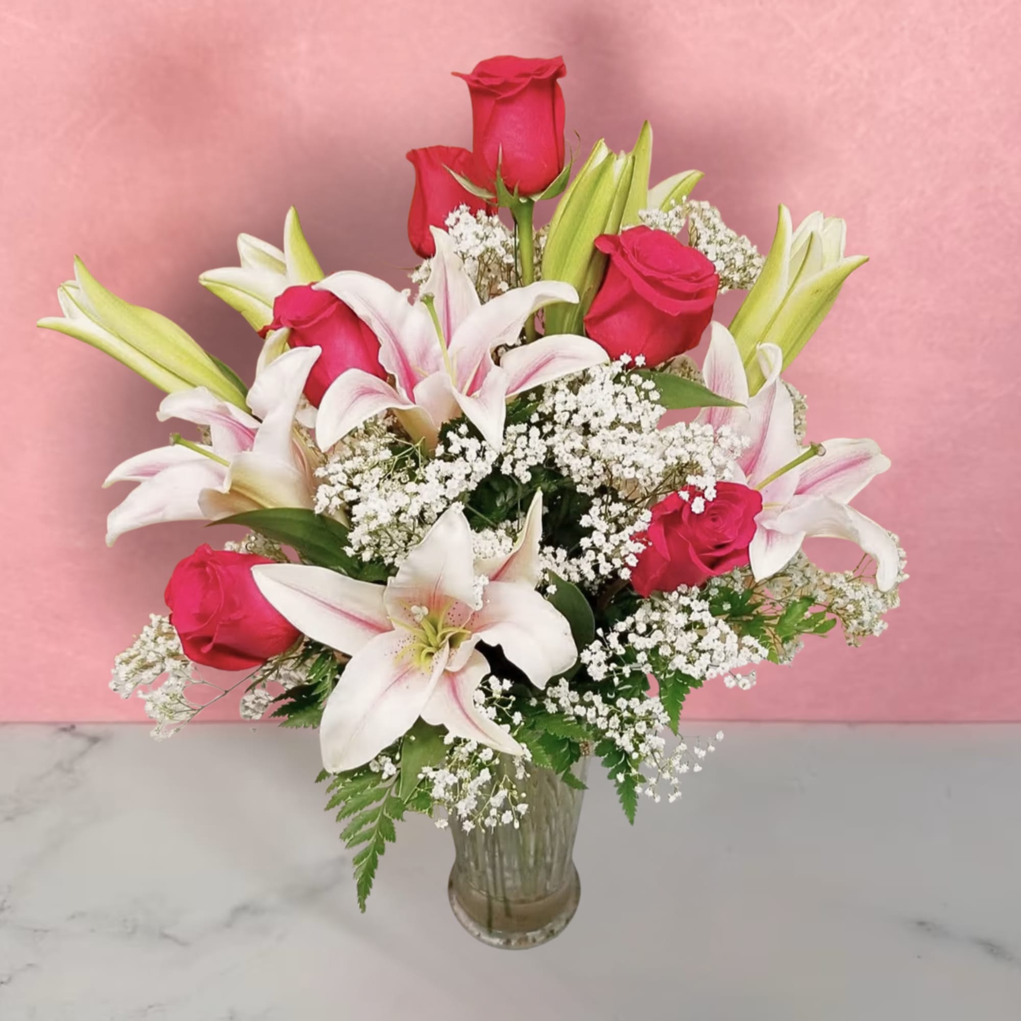 Bouquet of pink roses and white lilies in a clear glass vase
