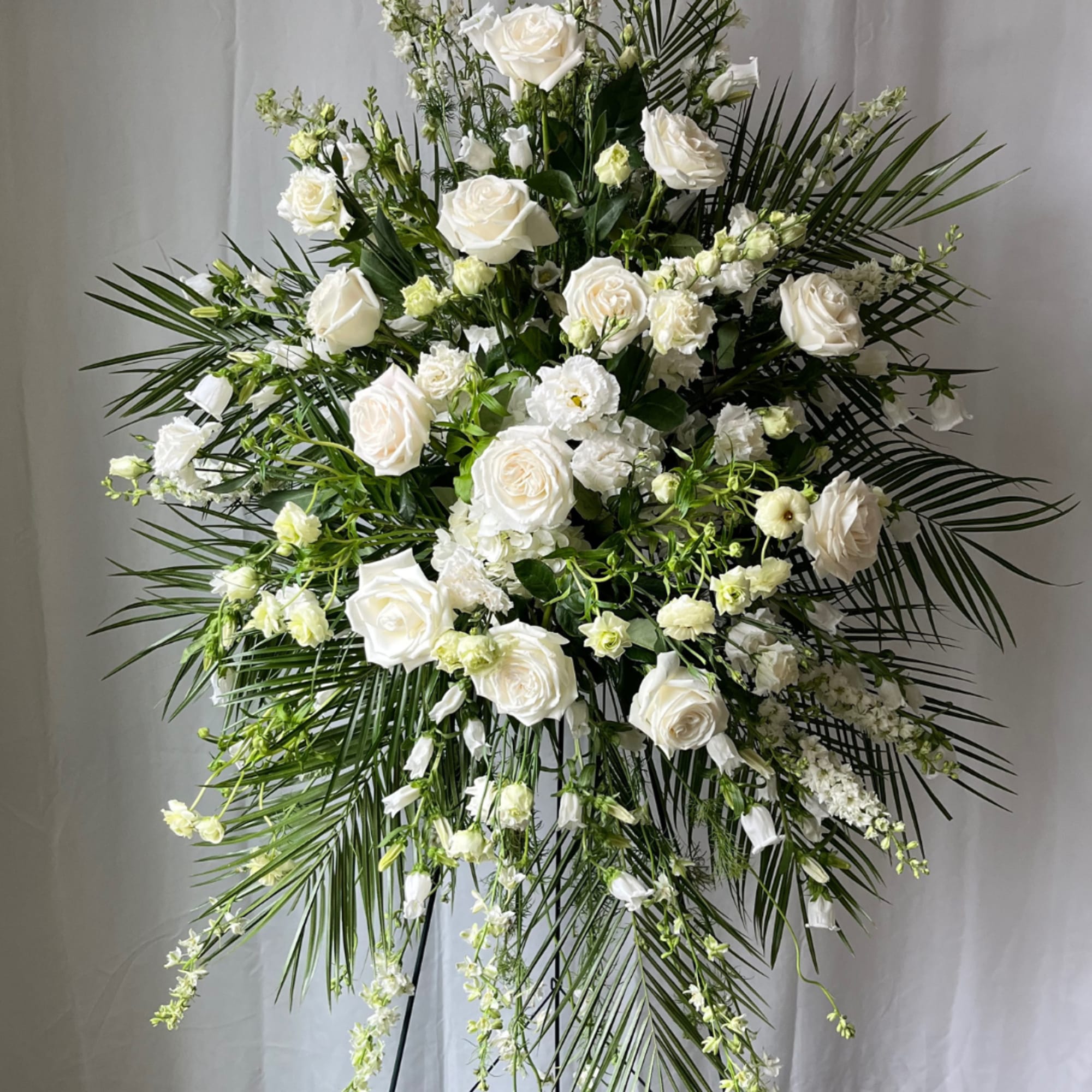 Large white floral standing spray with roses and palm fronds