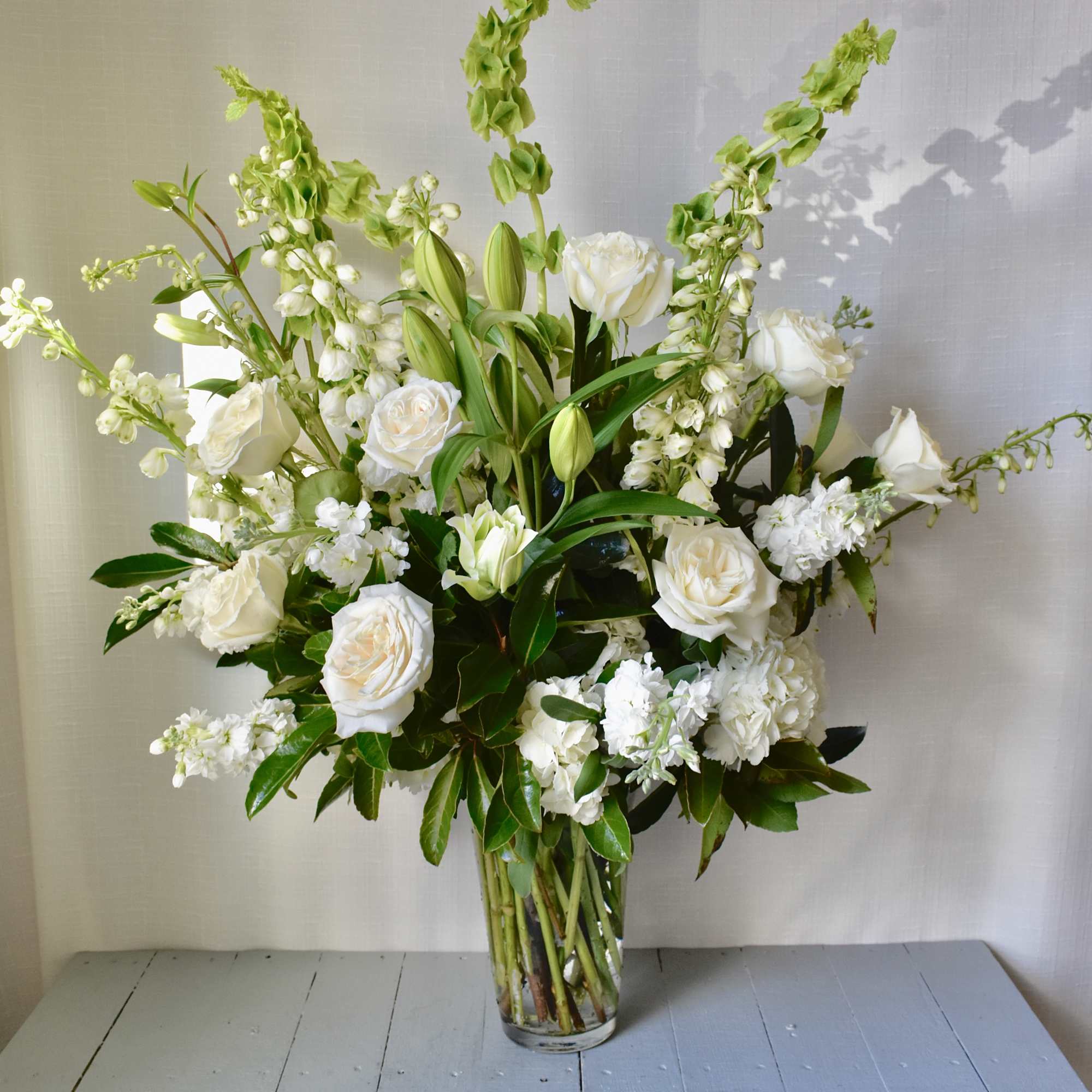 White floral arrangement in a clear glass vase with tall green spikes