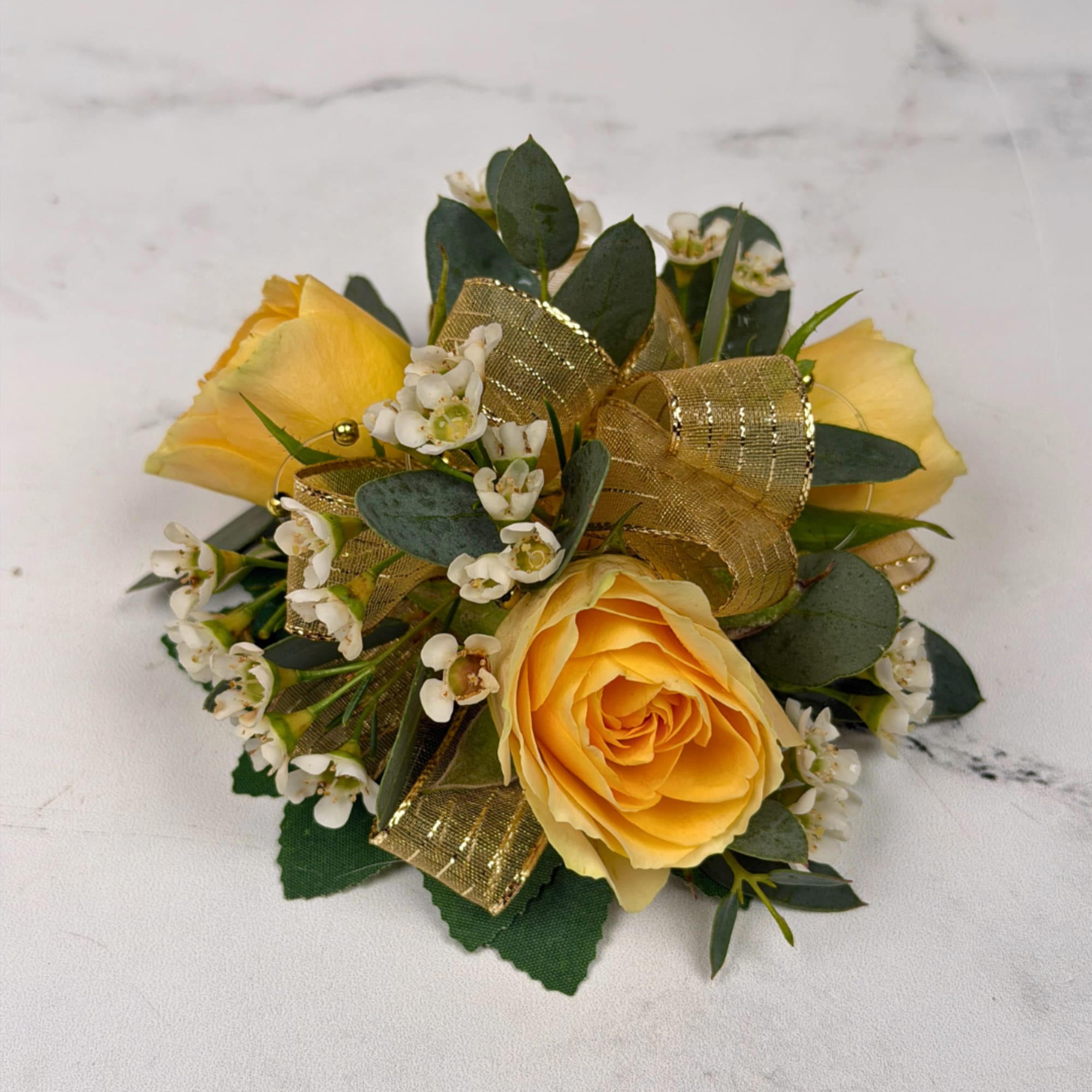 Three pale yellow spray roses form the heart of this wrist corsage