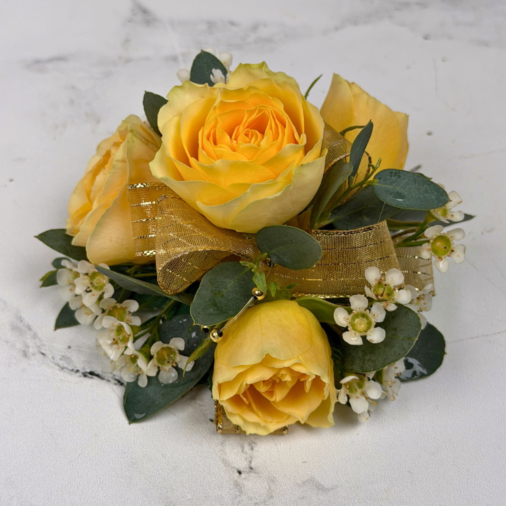 Four pale yellow spray roses form the heart of this wrist corsage