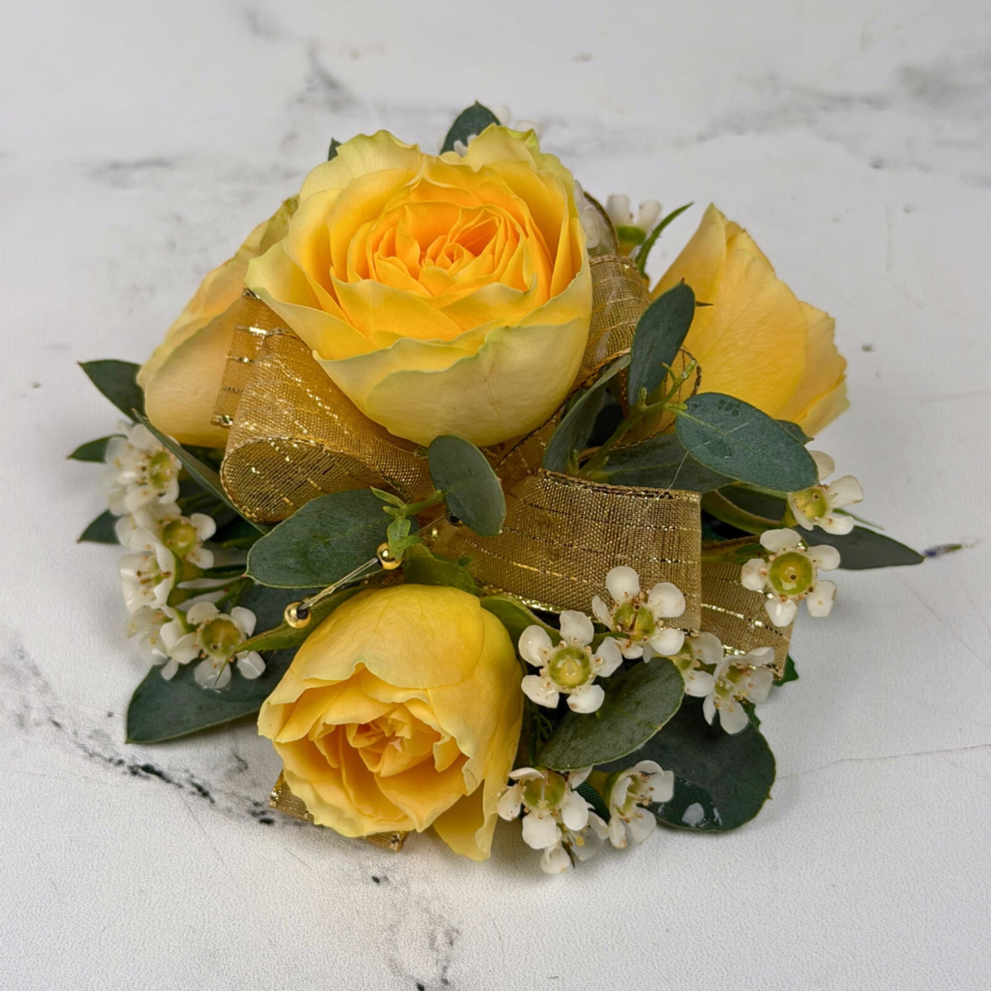 Four pale yellow spray roses form the heart of this wrist corsage