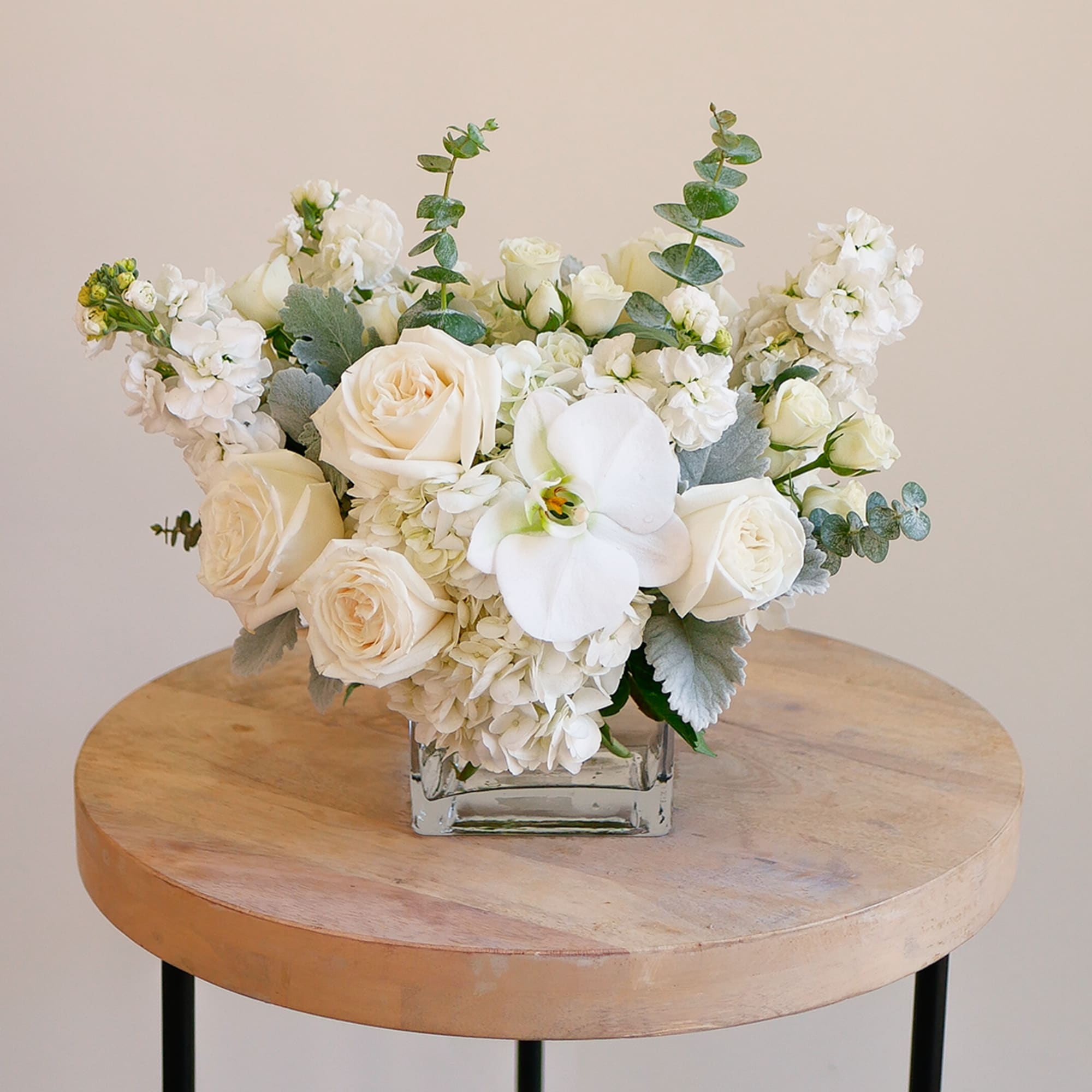 White rose arrangement in a square glass vase