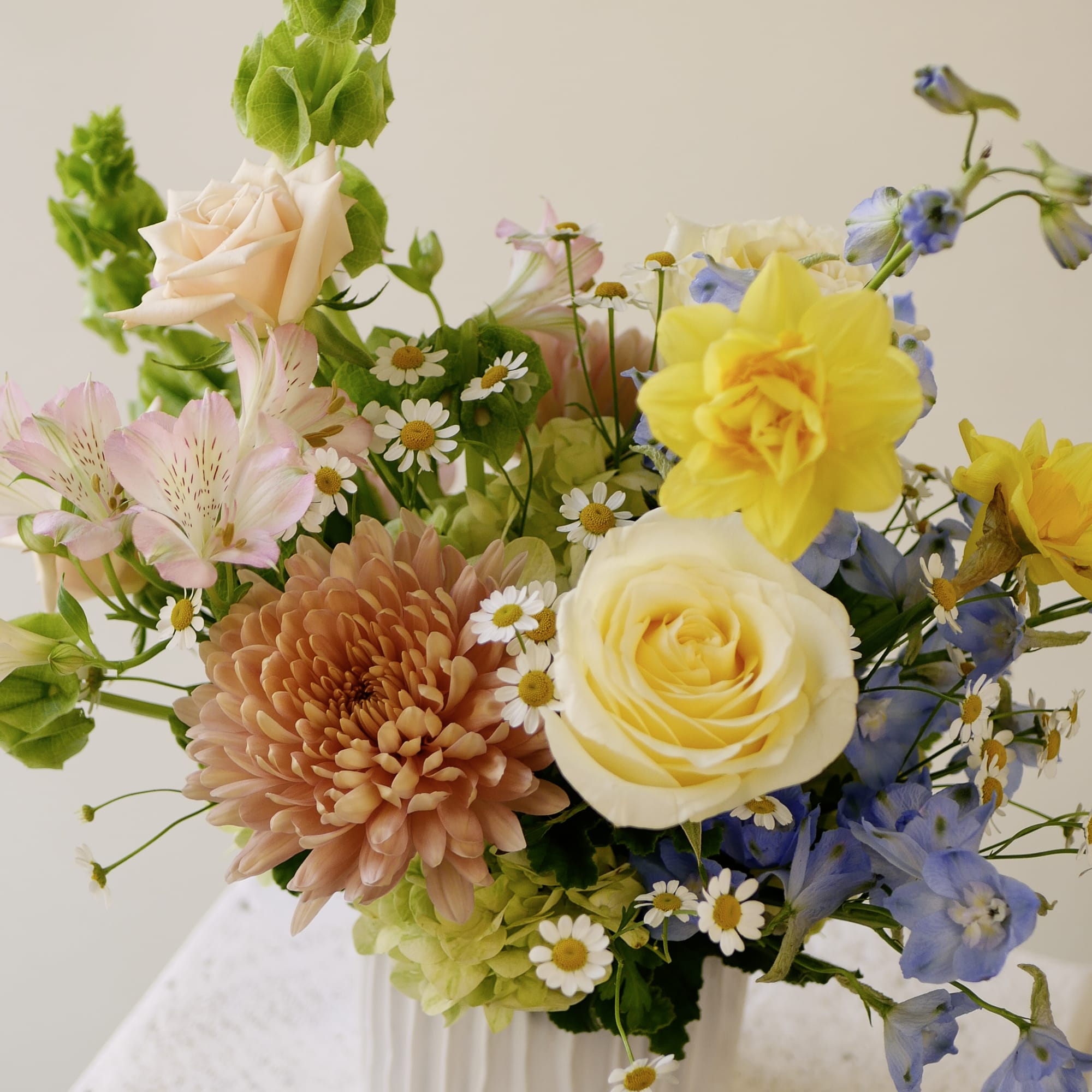 Soft yellow roses and daffodils take center stage, paired with sky blue