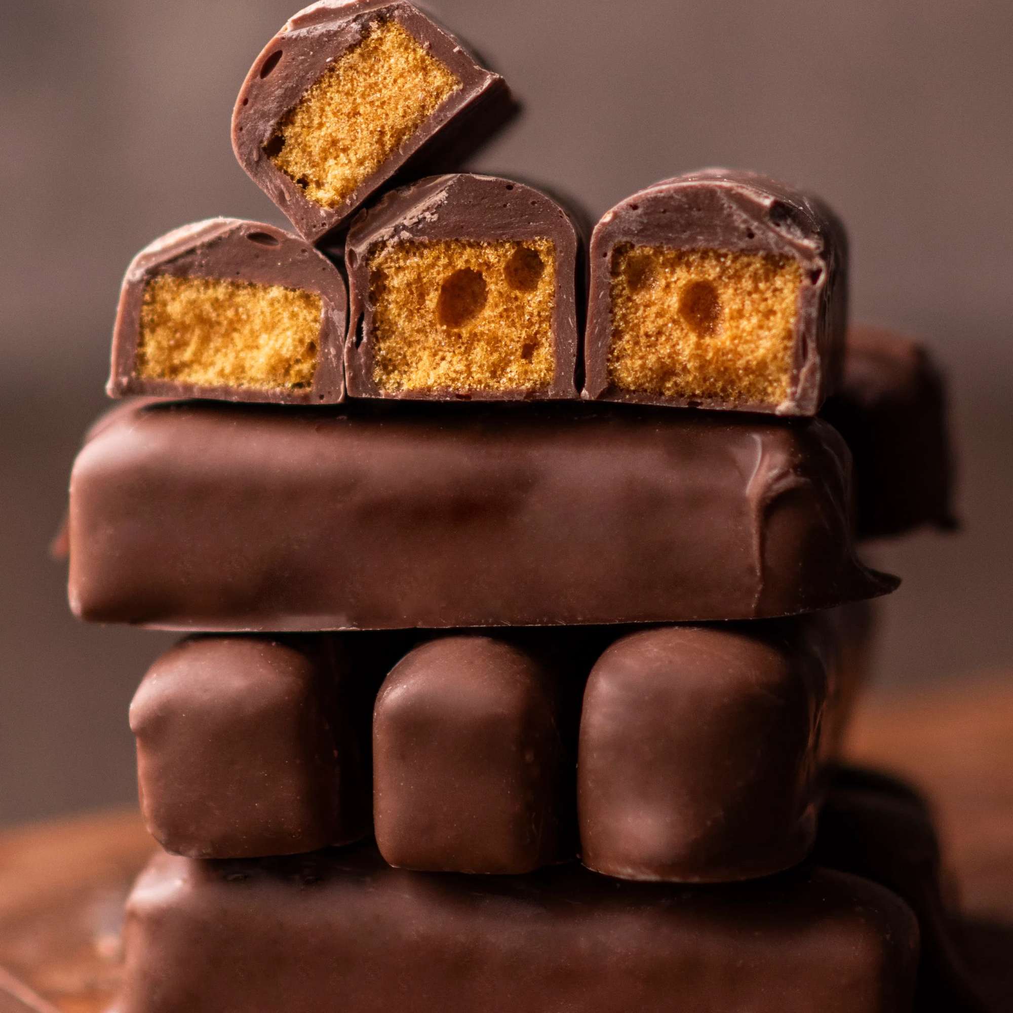 Stack of chocolate-covered candy bars with golden crunchy centers, some cut to show the inside.