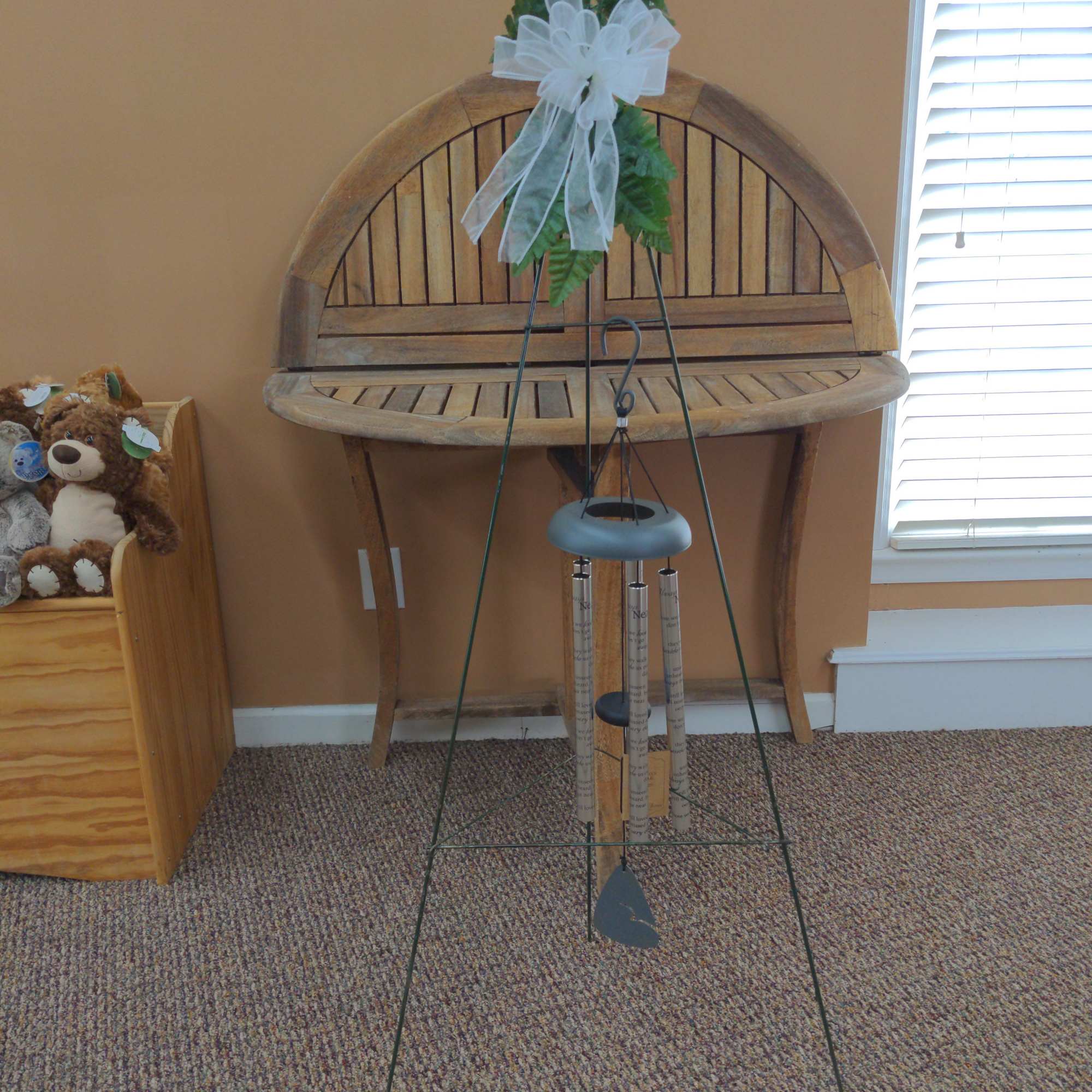Greenery tied with a white bow on a metal wind chime stand