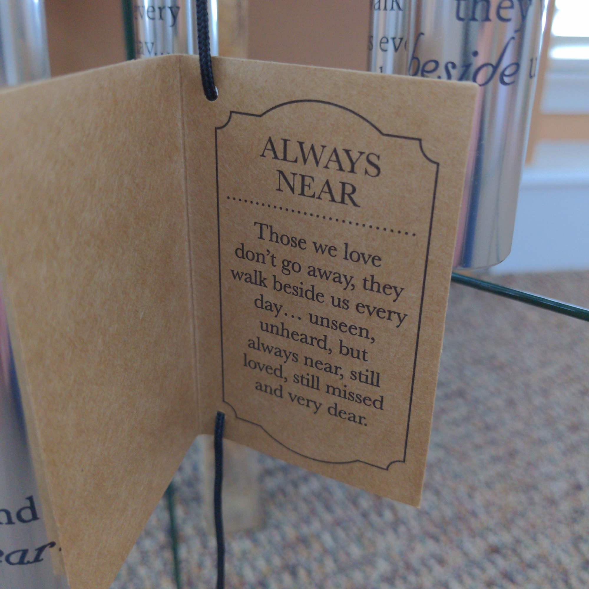 Hanging memorial tag with the words "Always Near" on a tan card