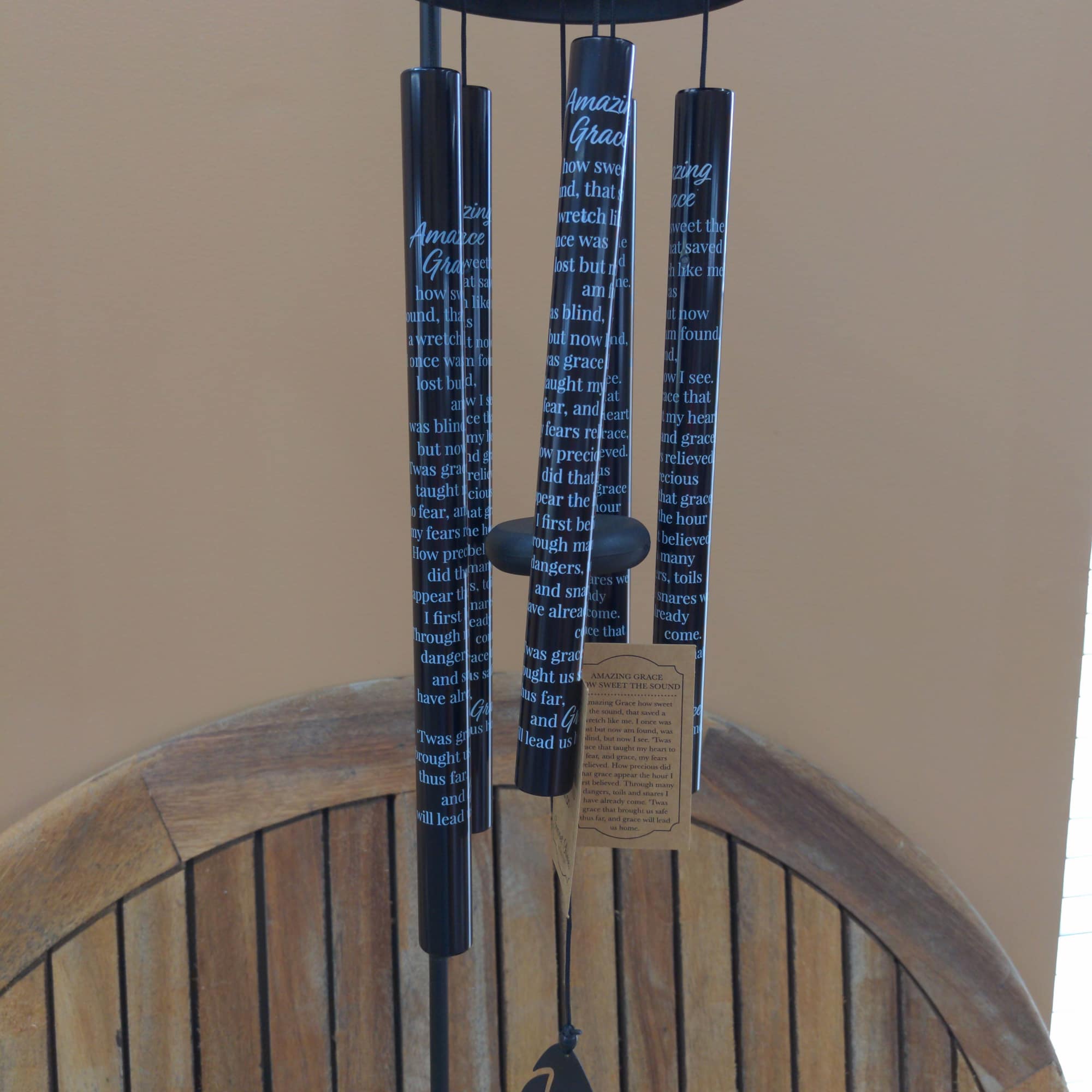 Black wind chime with printed text and a small hanging bird charm