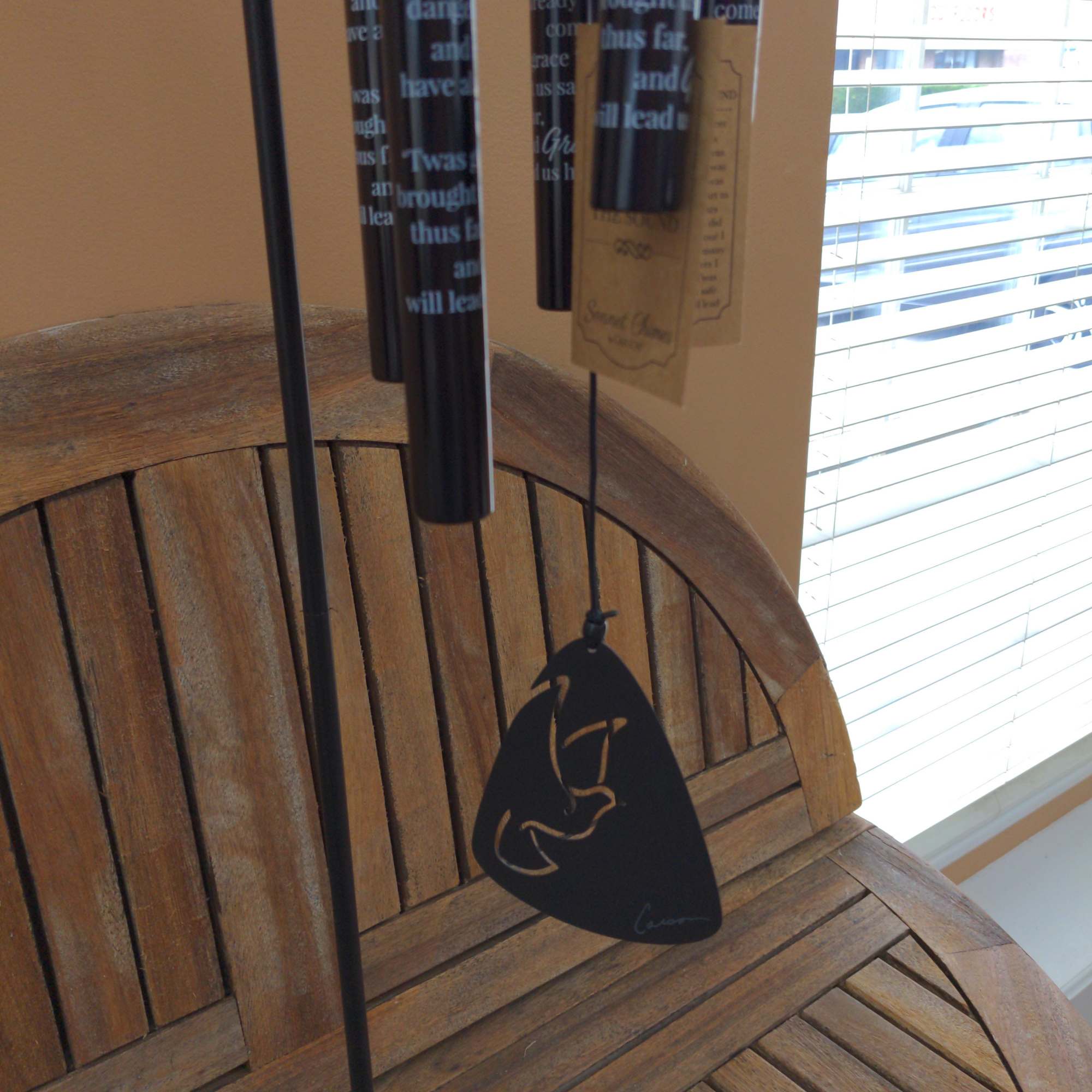 Black hanging wind chimes with a wooden chair in the background