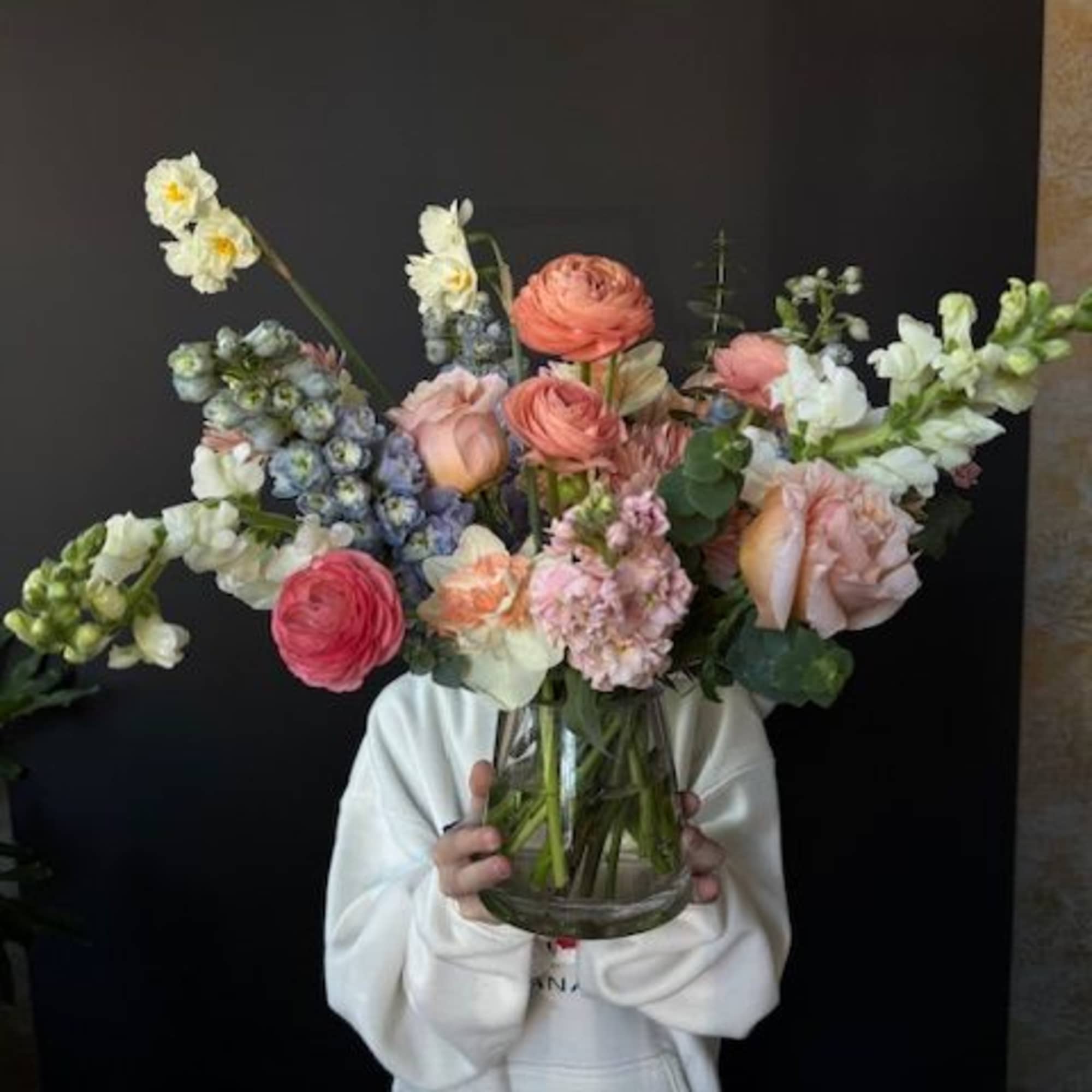 Large mixed bouquet in a clear glass vase with pink, white, and blue blooms