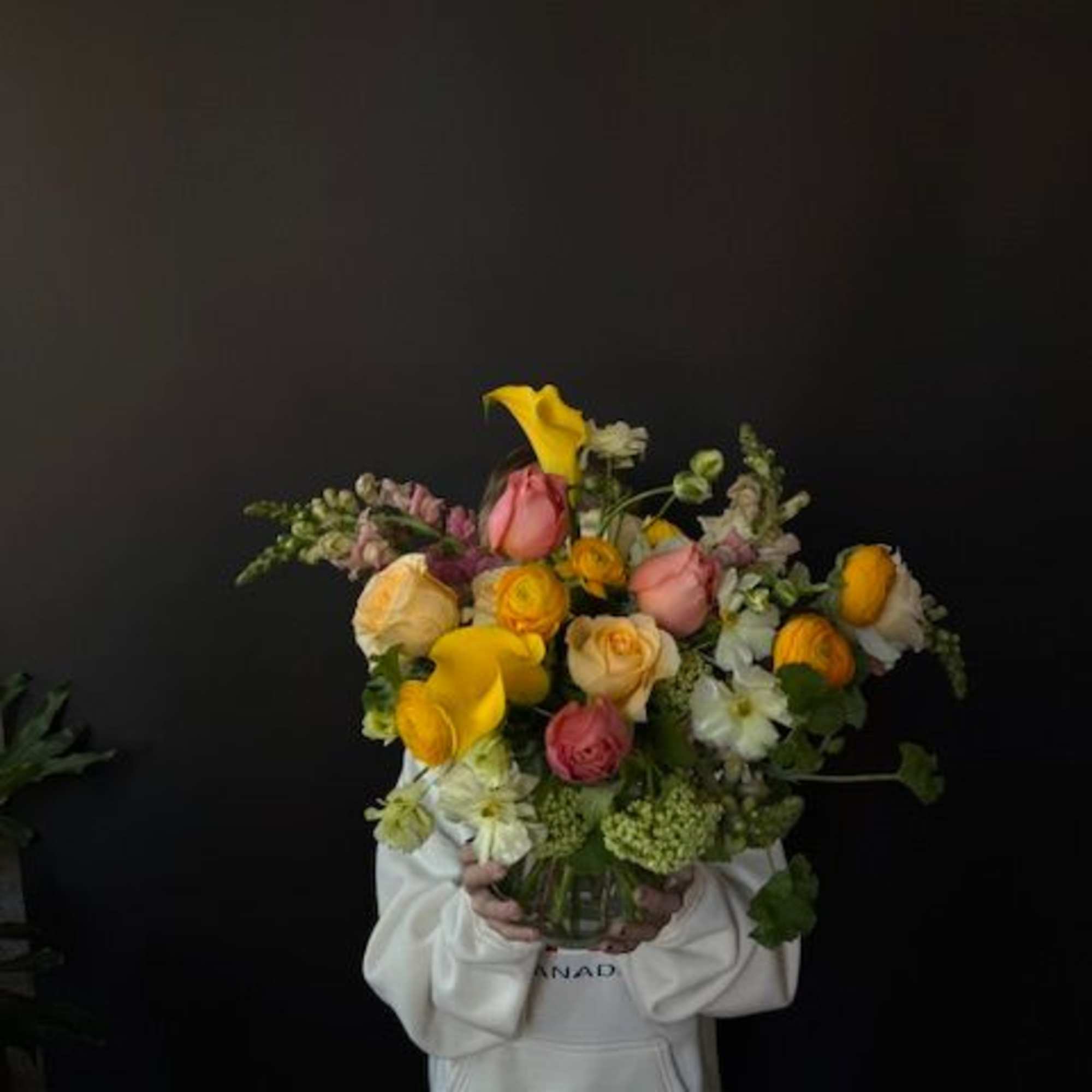 Large mixed bouquet of yellow, pink, and cream flowers in a glass vase