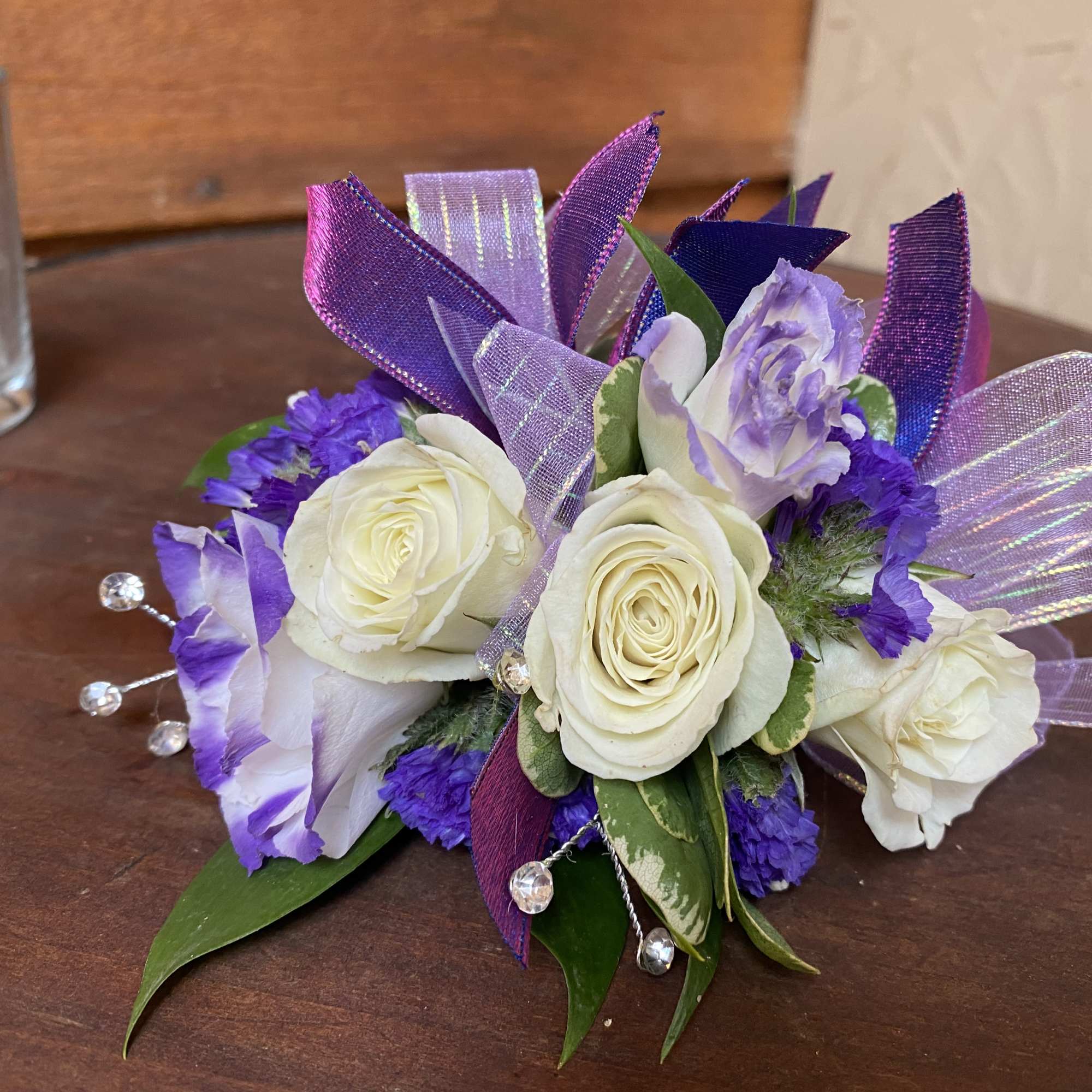 Purple and white floral corsage with ribbon accents on a table