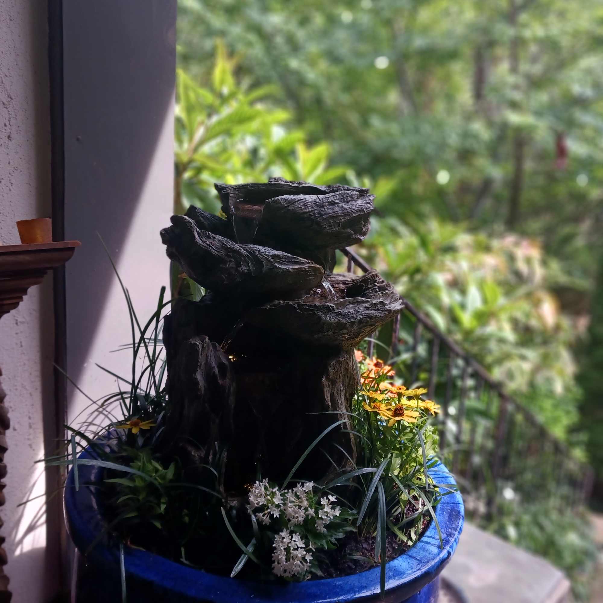 Blue planter with a small rock fountain and mixed flowers