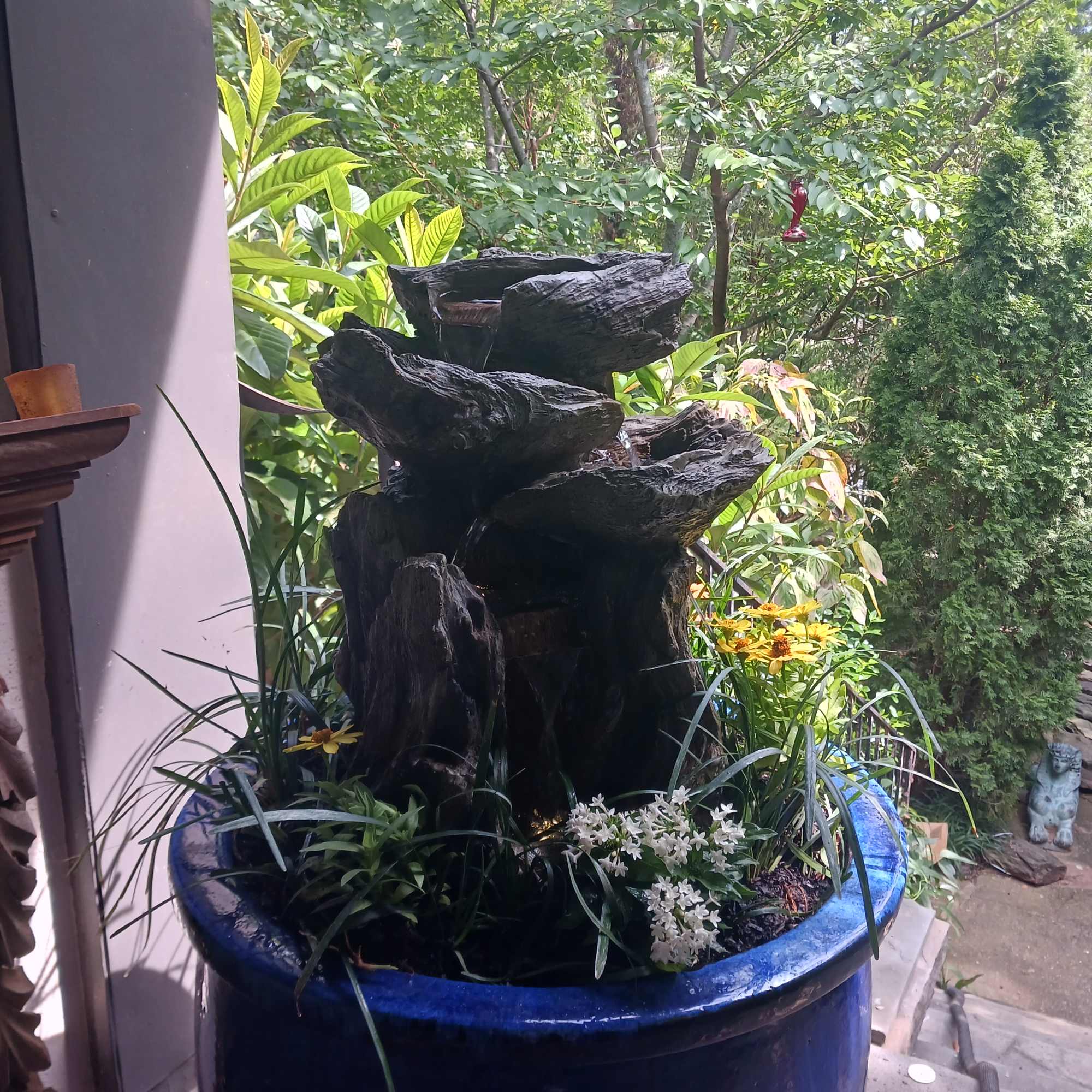 Large blue planter with a rock fountain and small flowers